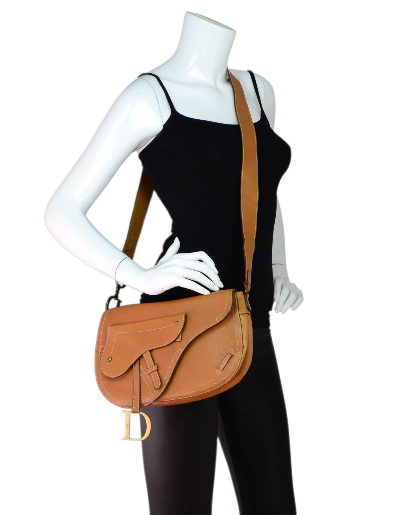 Christian Tan Leather D Buckle Messenger Saddle Bag

Made In: Italy
Color: Tan
Hardware: Goldtone
Materials: Leather, metal
Lining: Brown textile
Closure/Opening: Flap top with snap closure
Exterior Pockets: Small pocket at front and wall pocket at