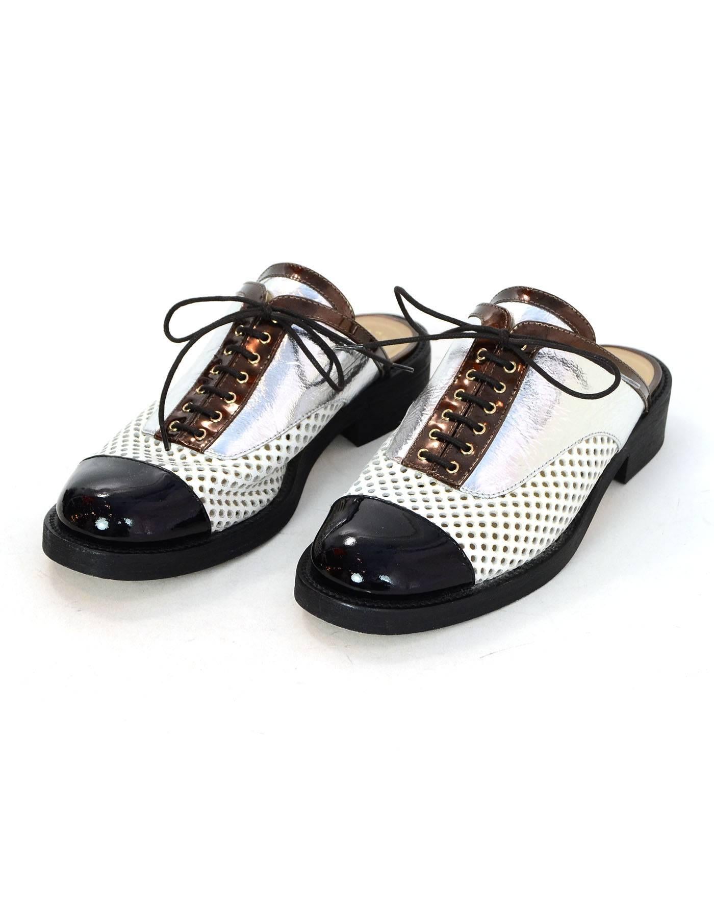 Chanel Black, White & Silver Paris/Cuba Perforated Mules Sz 40

Made In: Italy
Color: Black, white, silver, bronze
Materials: Leather, patent leather
Closure/Opening: Slide on with lace tie at vamp
Sole Stamp: CC 40 Made in Italy
Retail Price: