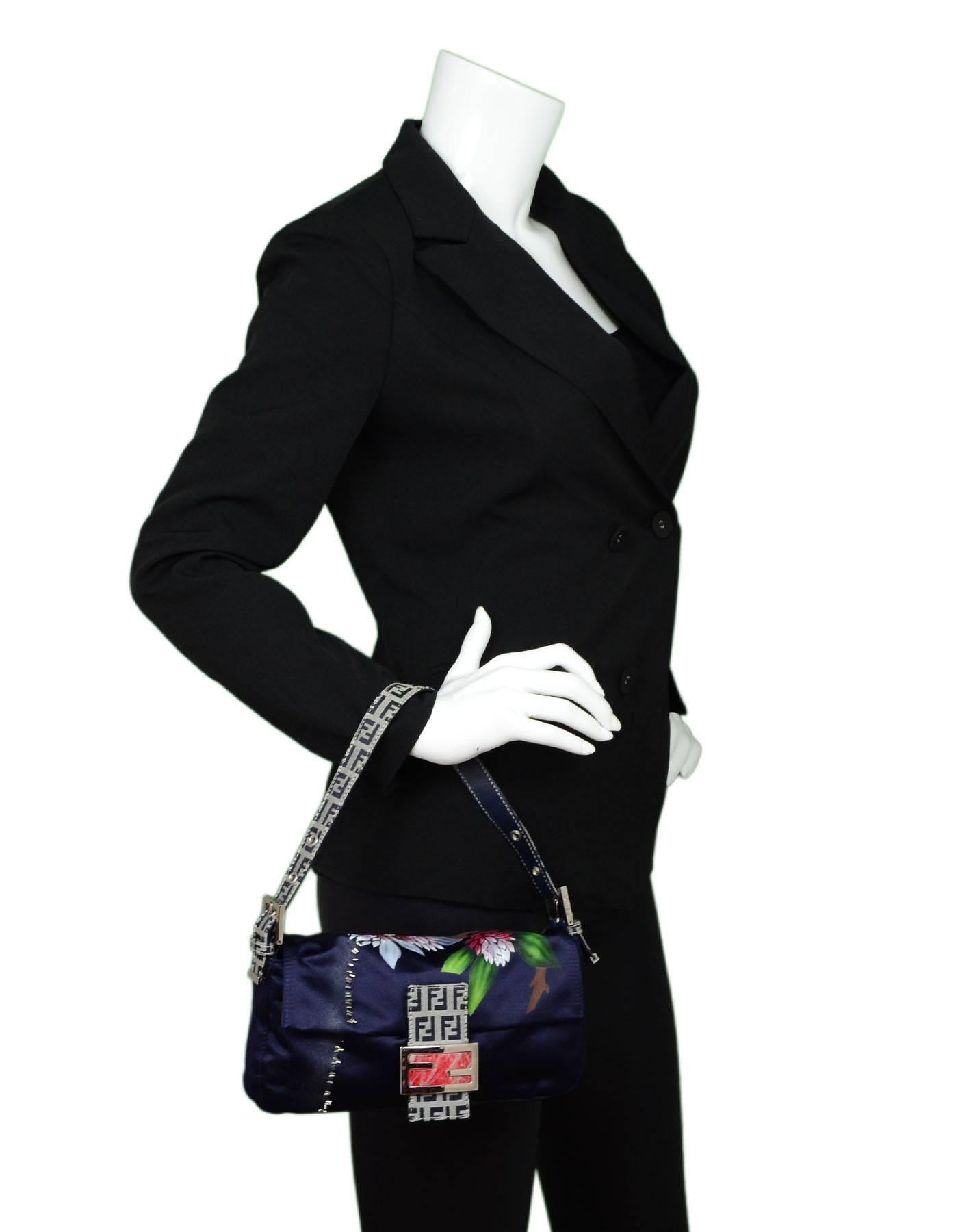 Fendi Navy Satin Floral Baguette
Features zucca strap and beading

Made In: Italy
Color: Navy, multi
Hardware: Silvertone
Materials: Satin, metal, beads
Lining: Navy textile
Closure/Opening: Flap top with magnetic snap closure
Exterior Pockets: