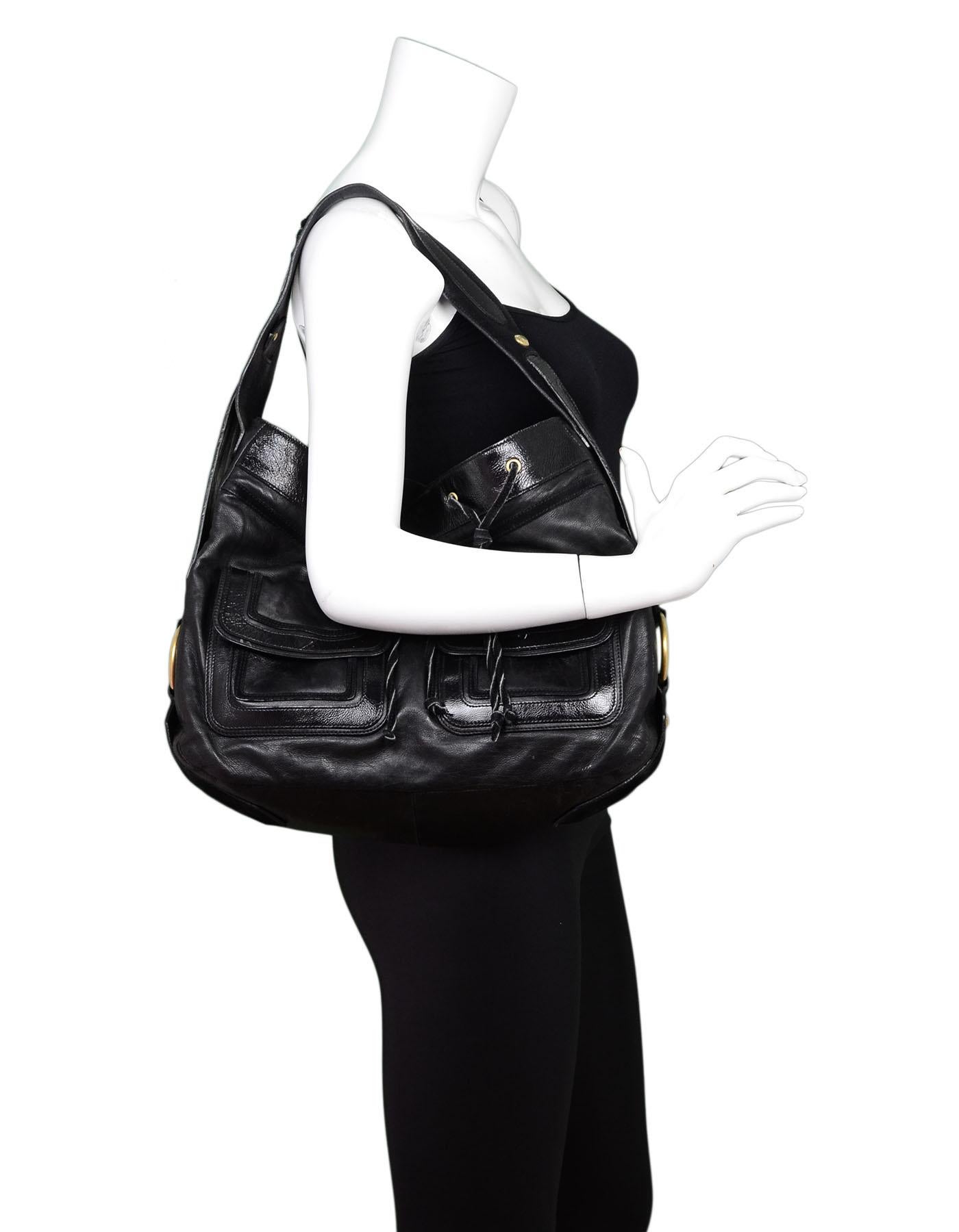 YSL Black Leather Drawstring Hobo

Made In: Italy
Color: Black
Hardware: Goldtone
Materials: Leather, patent leather, suede, metal
Lining: Black textile
Closure/Opening: Open top with center snap
Exterior Pockets: Two front flap pockets
Interior