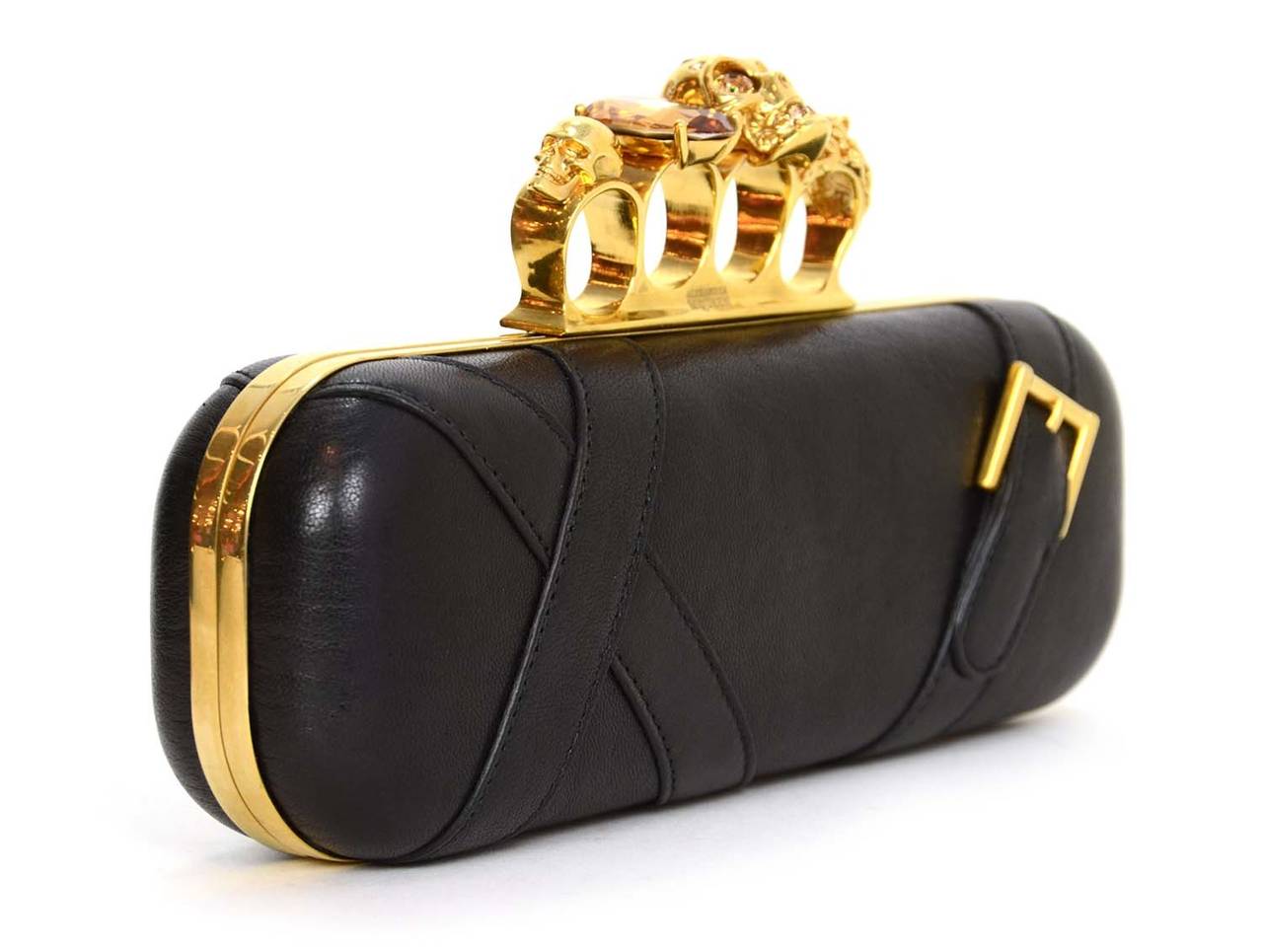 Alexander McQueen Black Leather Knuckle Clutch
Features skull and crystal detailing at knuckle finger holders

    Made in: Italy
    Color: Black and gold
    Hardware: Goldtone
    Materials: Leather and metal
    Lining: Black leather
   