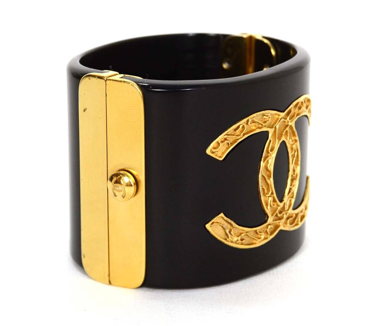 Chanel Black Resin & Goldtone Cuff
Features large goldtone CC on front
Made in: Italy
Year of Production: 2011
Stamp: B11 CC A
Closure: Hinge style opening with small CC button for push lock closure
Color: Black and goldtone
Materials: Resin