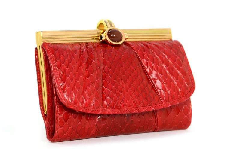 Red snakeskin with red leather lining.
Gold-tone frame.
Front snap w. red glass stone.
Front flap opens to reveal two pockets for bank notes and two slots for credit cards.