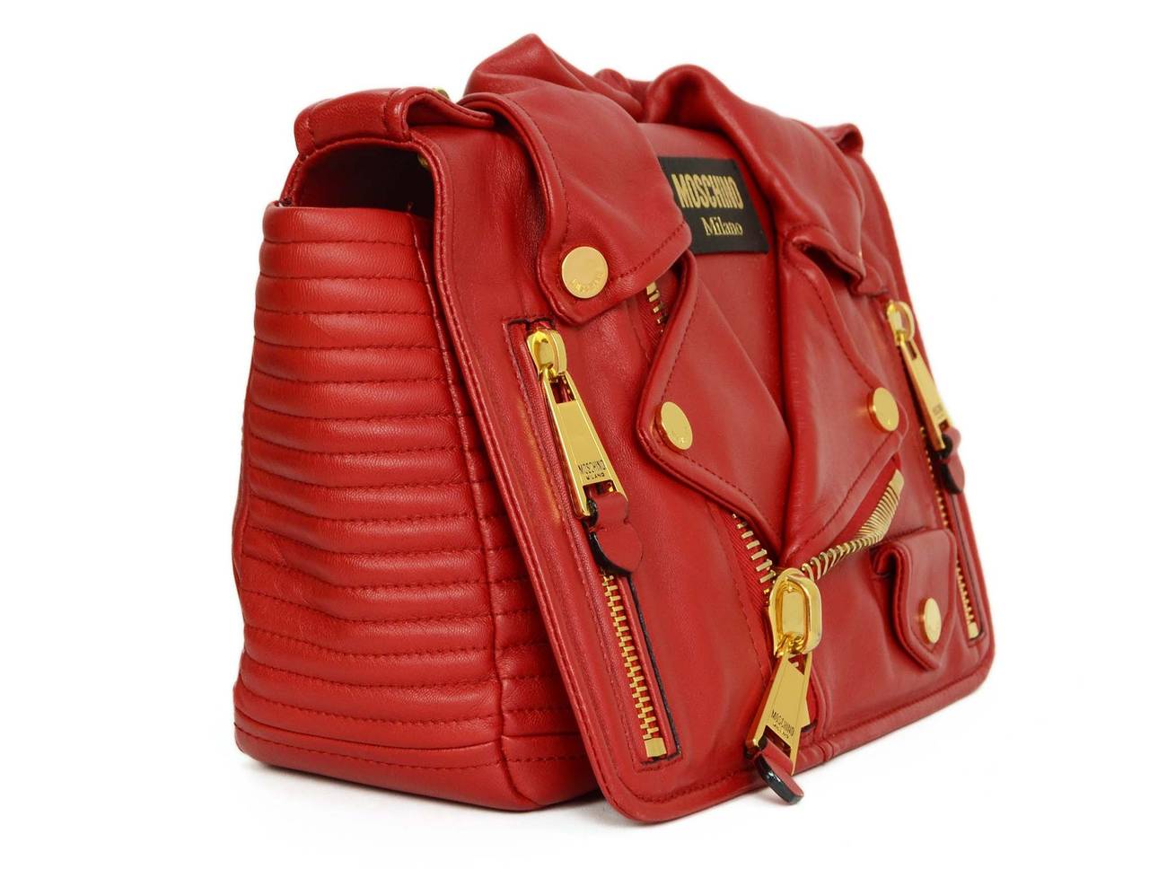 Moschino Red Leather Motorcycle Jacket Bag
Features all of the details that would go on a motorcycle jacket including buttons, zippers and a collar
Color: Red and goldtone
Hardware: Goldtone
Materials: Leather and metal
Lining: Black Moschino