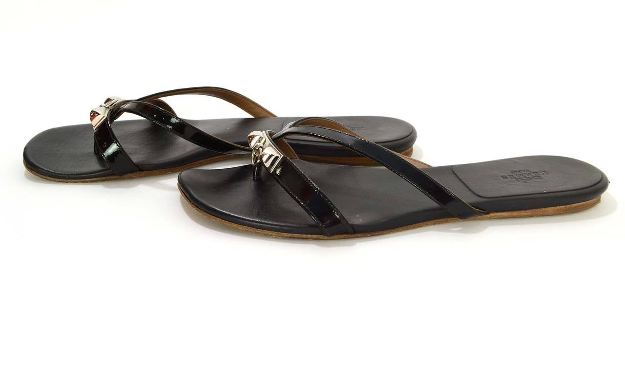 Hermes Black Patent Corfu Medor Sandals 
Features palladium medor knocker at toe straps
Made in: Spain
Color: Black and silvertone
Composition: Leather, patent, and palladium
Sole Stamp: Hermes, 37 1/2 Semelle Cuir Made in