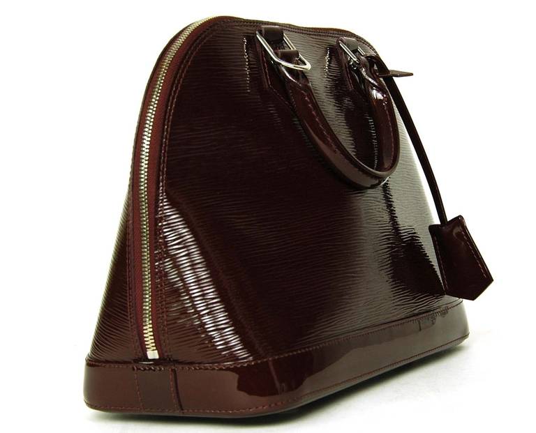 Electric Epi patent leather in a deep prune/wine color
Burgundy alcantara lining
Silvertone hardware.
Alma style with two rolled leather handles
Top zip with hanging padlock
Dangling clochette with keys.
Four protective feet at base.