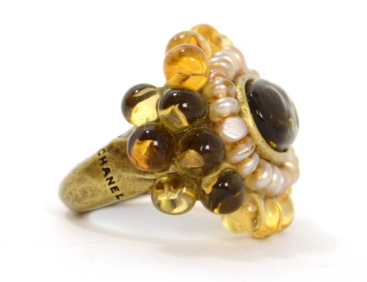 Chanel Pearl & Amber Glass Ring
Features poured glass and faux pearl intricate pendant

Made In: France
Year of Production: 2000
Color: Bronze, amber and ivory
Materials: Metal, faux pearl and poured glass
Closure: None
Stamp: 00 CC