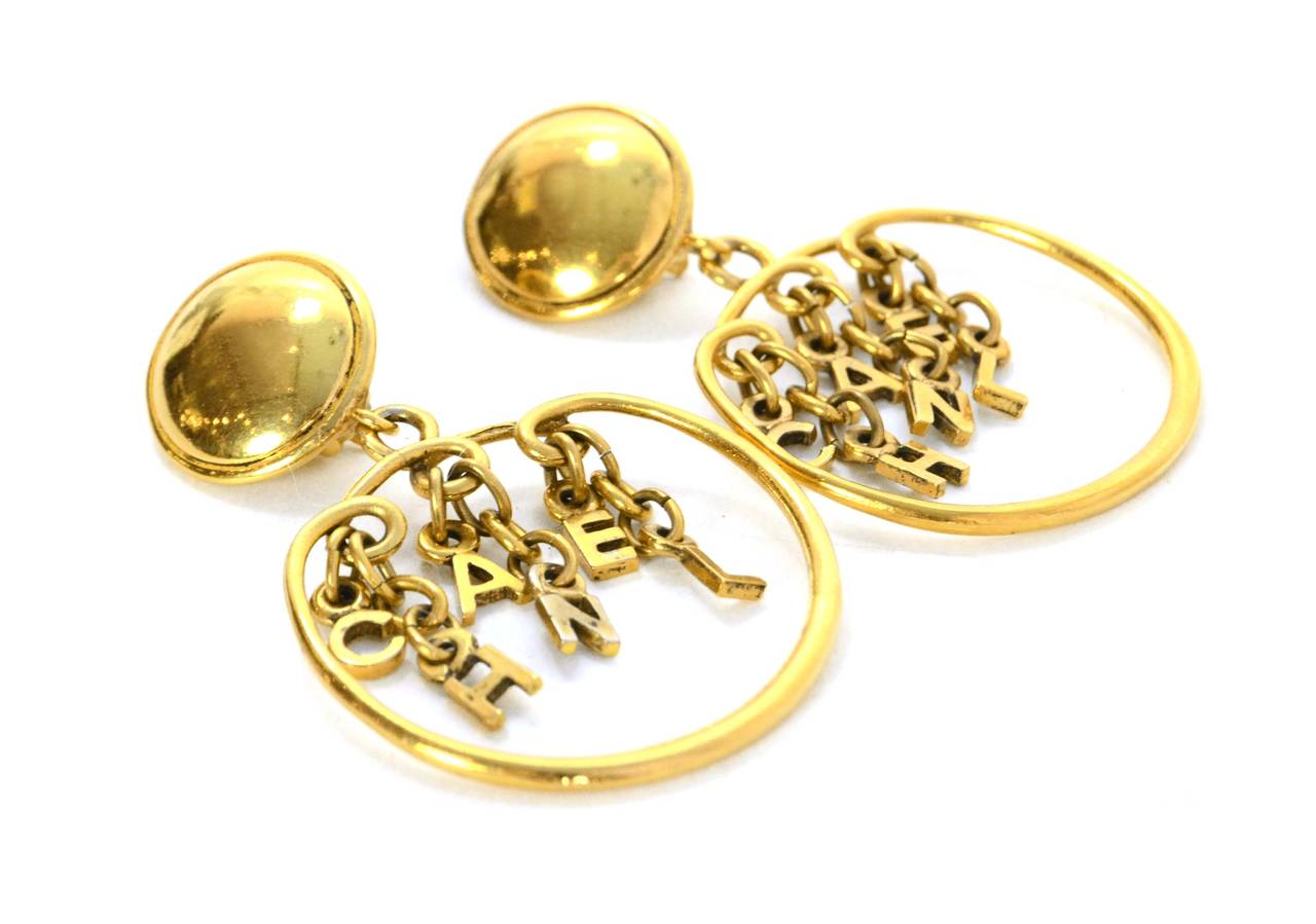 Chanel Vintage '80s Gold Charm Hoop Clip On Earrings 
Features Chanel spelled out in charms dangling through hoops
Made In: France
Year of Production: 1980's
Color: Goldtone
Materials: Metal
Closure: Clip on
Stamp: Chanel CC Made in