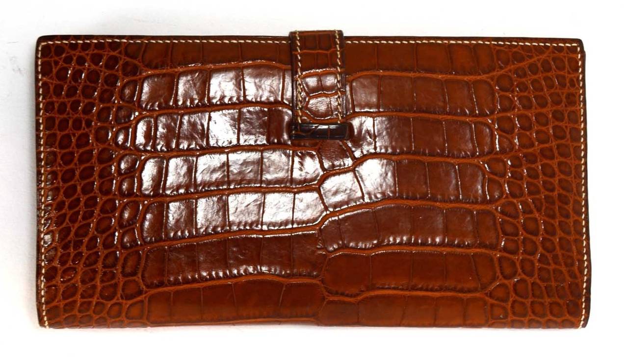 -Made in: France
-Year of Production: 2004
-Color: Cognac brown with white contract stitching.
-Materials: Alligator, metal
-Hardware: Goldtone
-Lining: Cognac chevre leather
-Exterior Pockets: N/A
-Interior Pockets: Five credit card slots, Four