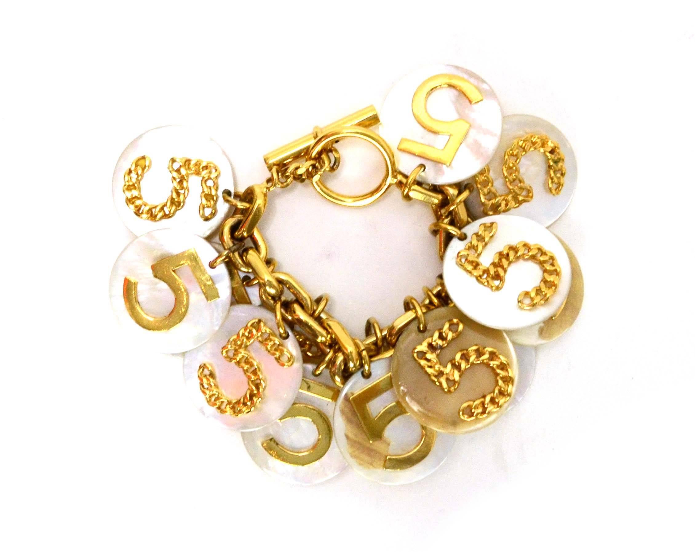 Chanel Vintage '60s Mother of Pearl #5 Charm Bracelet 
Features goldtone 5's on each MOP disc with one side as a chain link 5

Color: Goldtone and iridescent ivory
Materials: Mother of pearl and metal
Closure: Toggle closure
Stamp: