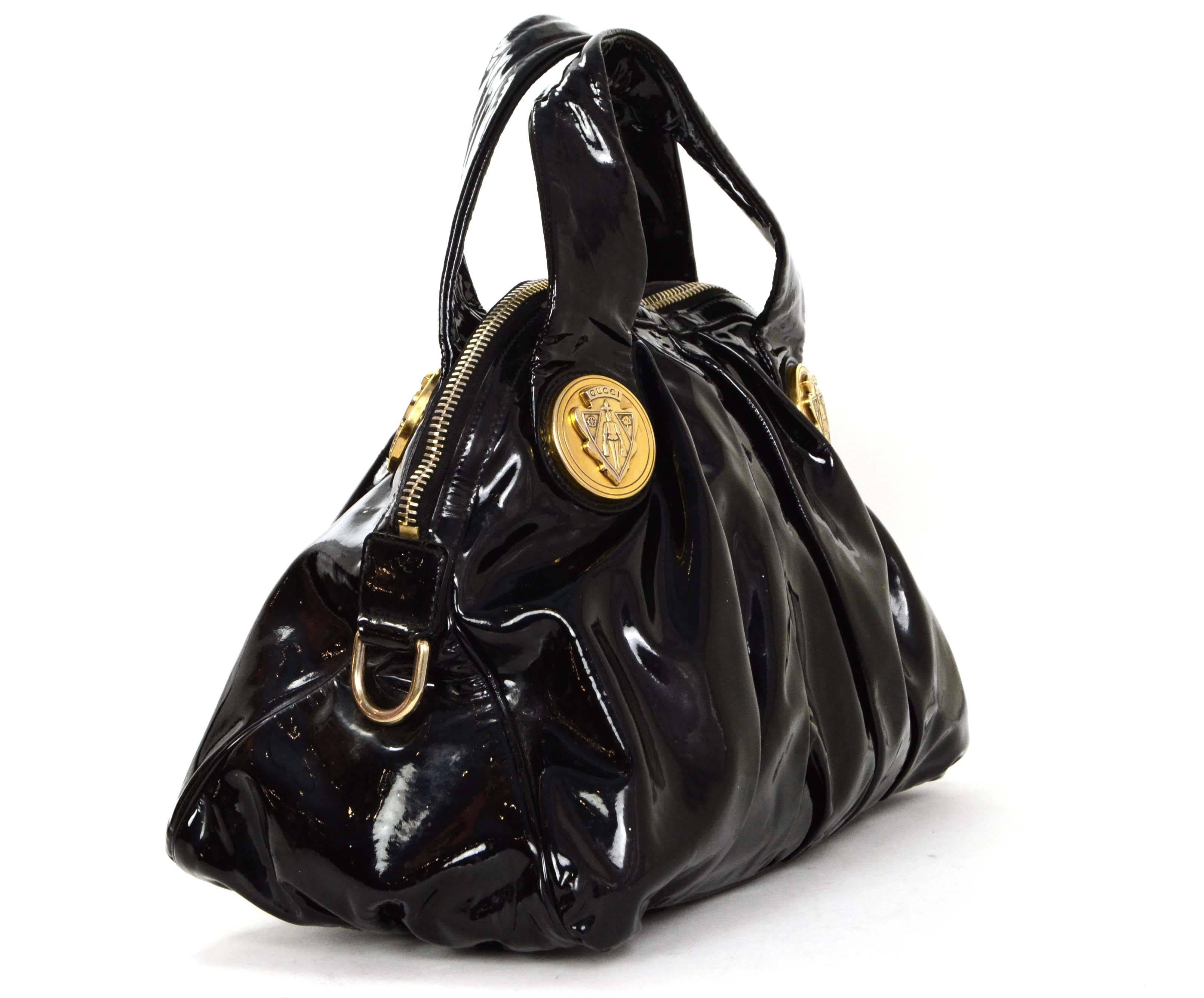 Gucci Black Patent Medium Hysteria Tote 
Features large goldtone metal Gucci emblems on both sides of bag
Made In: Italy
Color: Black
Hardware: Goldtone
Materials: Patent leather
Lining: Black Gucci logo textile
Closure/Opening: Zip around