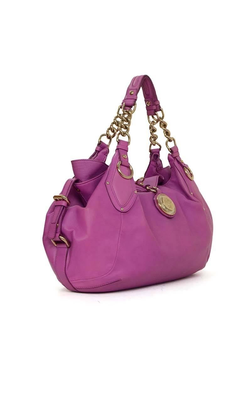 Versace Purple Leather Shoulder Bag 
Features adjustable sides
Made In: Italy
Year Of Production: 2009
Color: Purple
Hardware: Goldtone
Materials: Leather and metal
Lining: Purple satin
Closure/Opening: Open top with lever that goes over