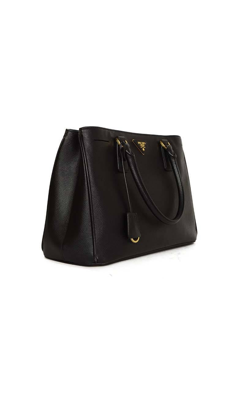 Prada Black Saffiano Lux Small Gardener's Tote 
Features optional shoulder/crossbody strap
Made In: Italy
Year of Production: 2014
Color: Black (Cammeo 1)
Hardware: Goldtone
Materials: Saffiano leather
Lining: Black textile
Closure/Opening: