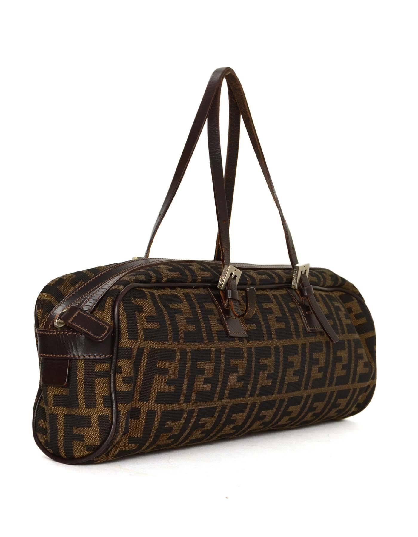Fendi Zucca Print Canvas Baguette 
Features adjustable shoulder straps
Made In: Italy
Color: Brown and black
Hardware: Silvertone
Materials: Canvas and leather
Lining: Brown nylon
Closure/Opening: Zip across top
Exterior Pockets: