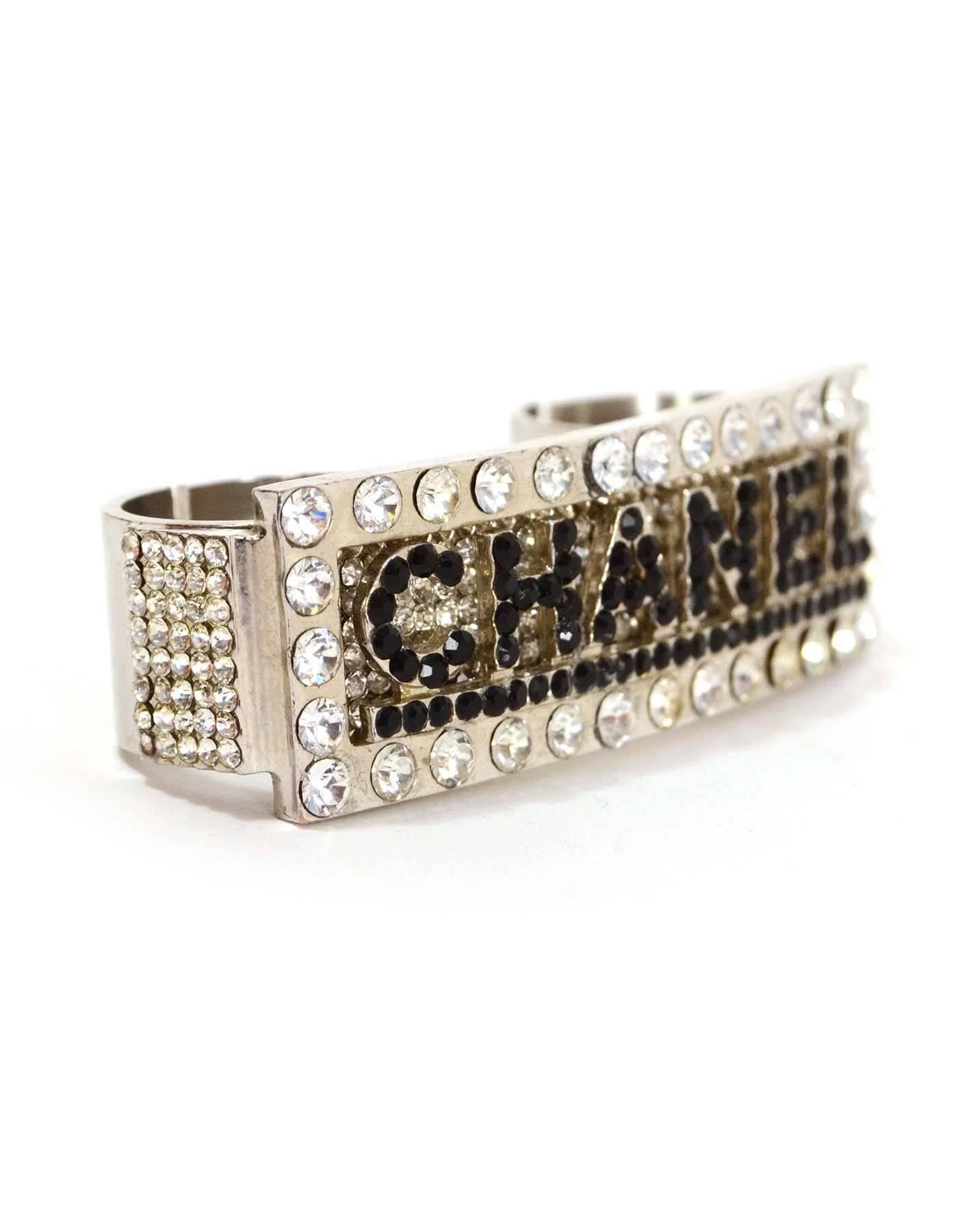 Chanel Black Crystal & Silver Double Knuckle Ring 
Features Chanel spelled out in black crystals on bar surrounded by clear crystals
Color: Silvertone, black and clear
Materials: Metal and crystal
Closure: None- open space on ring bands to