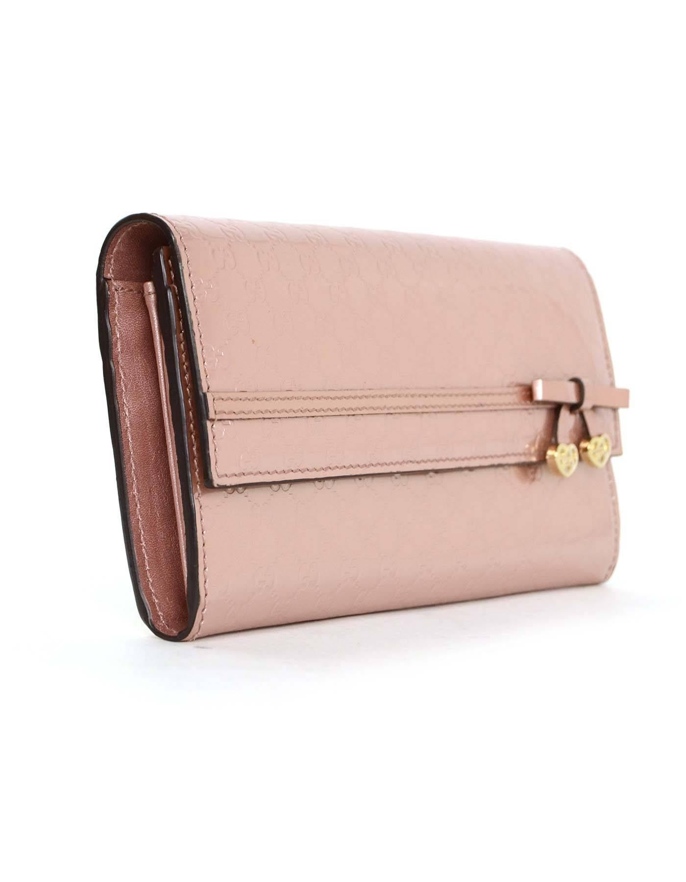 Features bow detail with goldtone logo engraved hearts

-Made In: Italy
-Color: Champagne pink
-Materials: Patent leather and metal
-Lining: Champagne pink leather
-Closure/Opening: Flap snap
-Exterior Pockets: None
-Interior Pockets: One