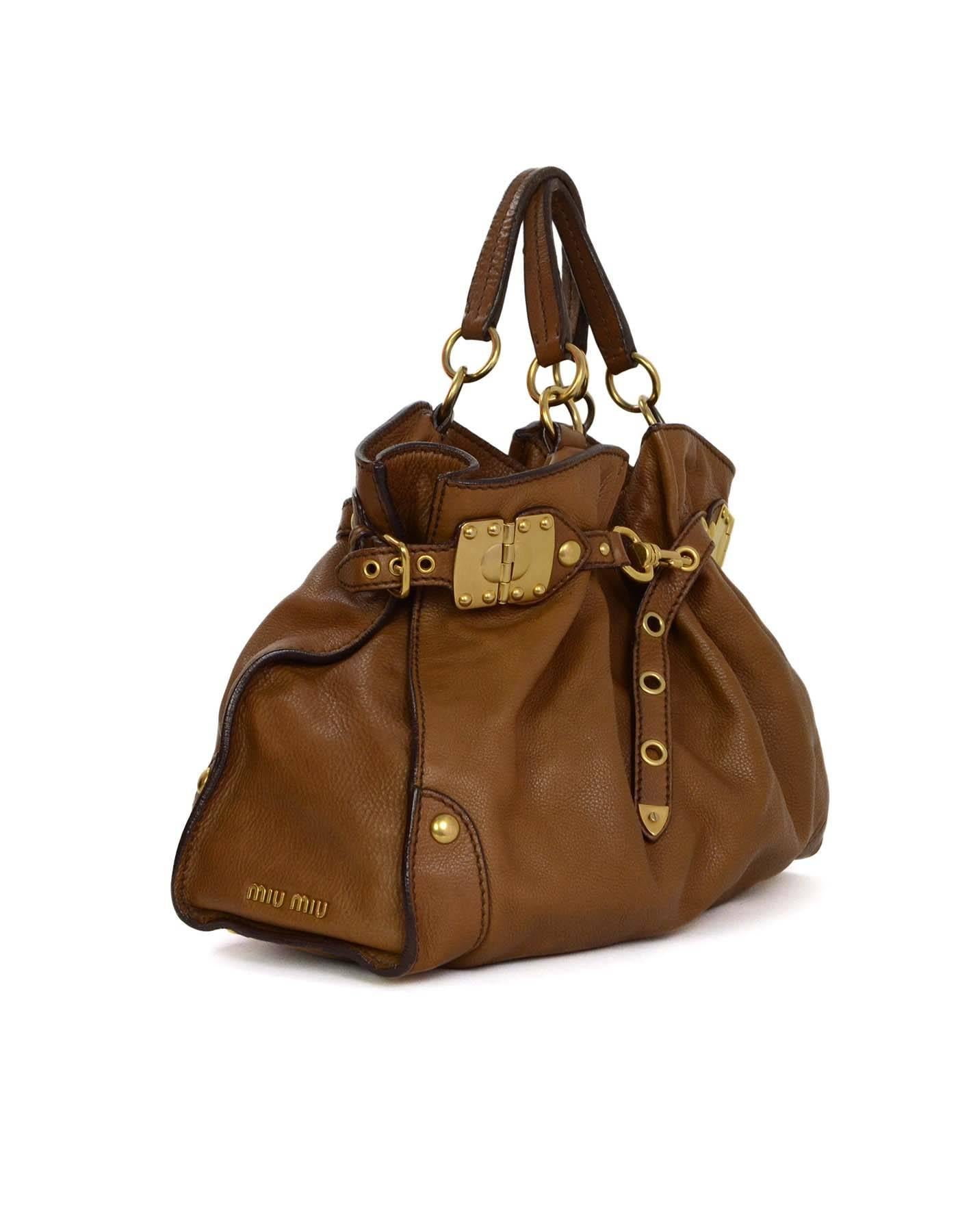 Miu Miu Tan Leather Belt Buckle Tote 
Features gold hinges, grommets and buckles on both sides of bag for expanding and cinching
Made In: Italy
Color: Tan
Hardware: Goldtone
Materials: Leather
Lining: Brown canvas
Closure/Opening: Open top