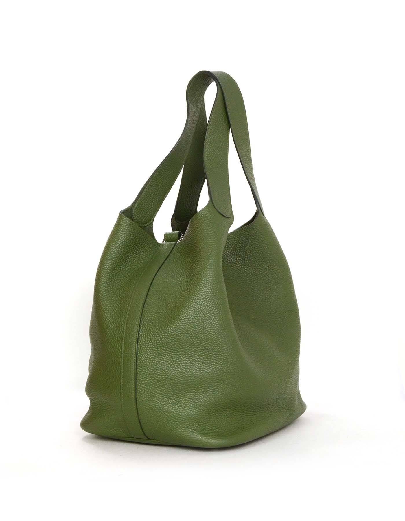 Features open top with strap that closes with oversized lock. Five metal feet protect bottom of the bag.

    Made In: France
    Color: Olive green
    Hardware: Silvertone palladium
    Materials: Clemence leather
    Lining: Green suede
  