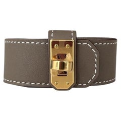 Hermes, NUEVO EN SU CAJA, Kelly Twist PM de piel gris etoupe con pulsera, talla T3