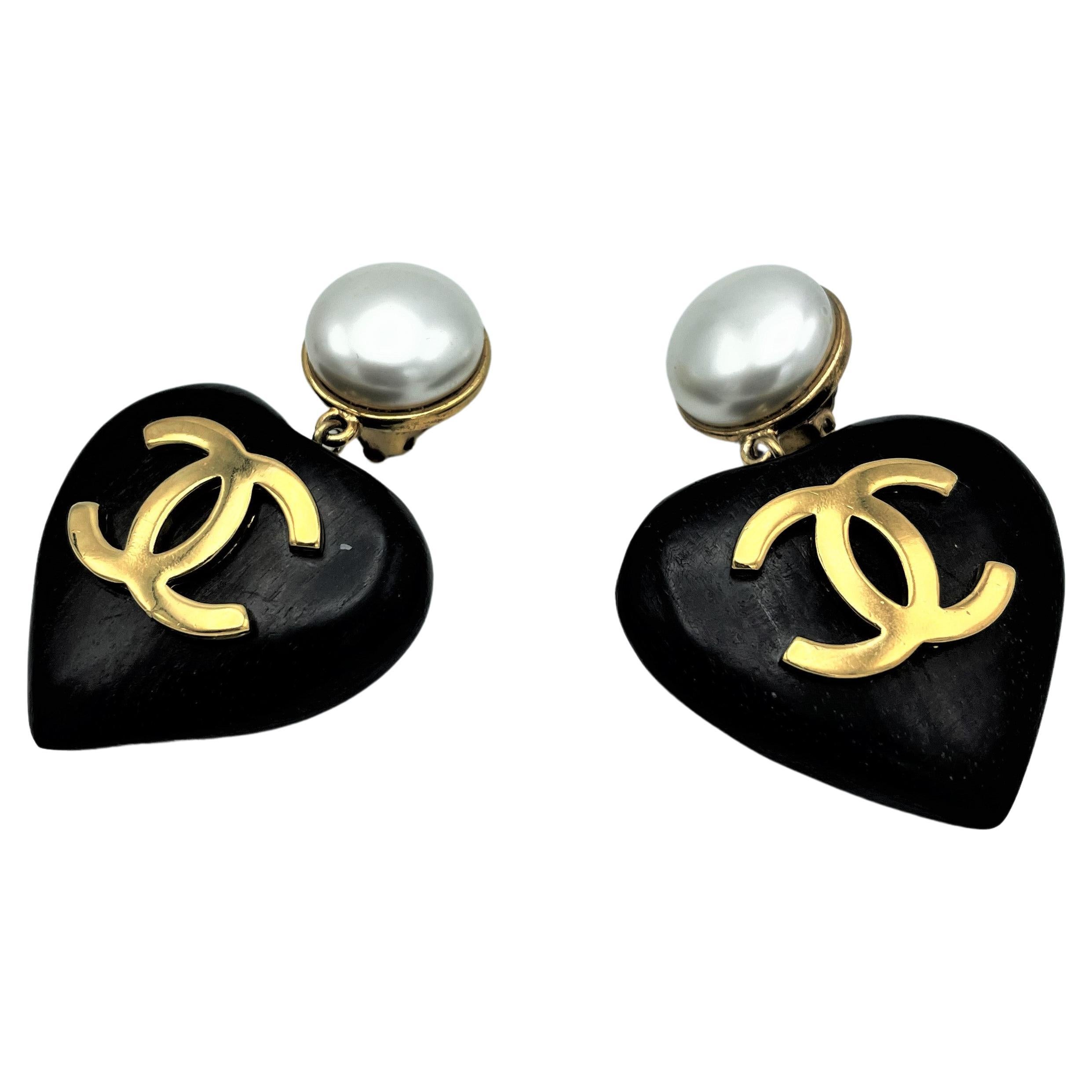 These are the most wanted vintage CHANEL wood heart clip-on earring!
Very rare and iconic ear clips with a large faux pearl, hanging from it a large black ebony heart with 2 attached large CCs signed 2CC8. This earrings are designed from Victoire de