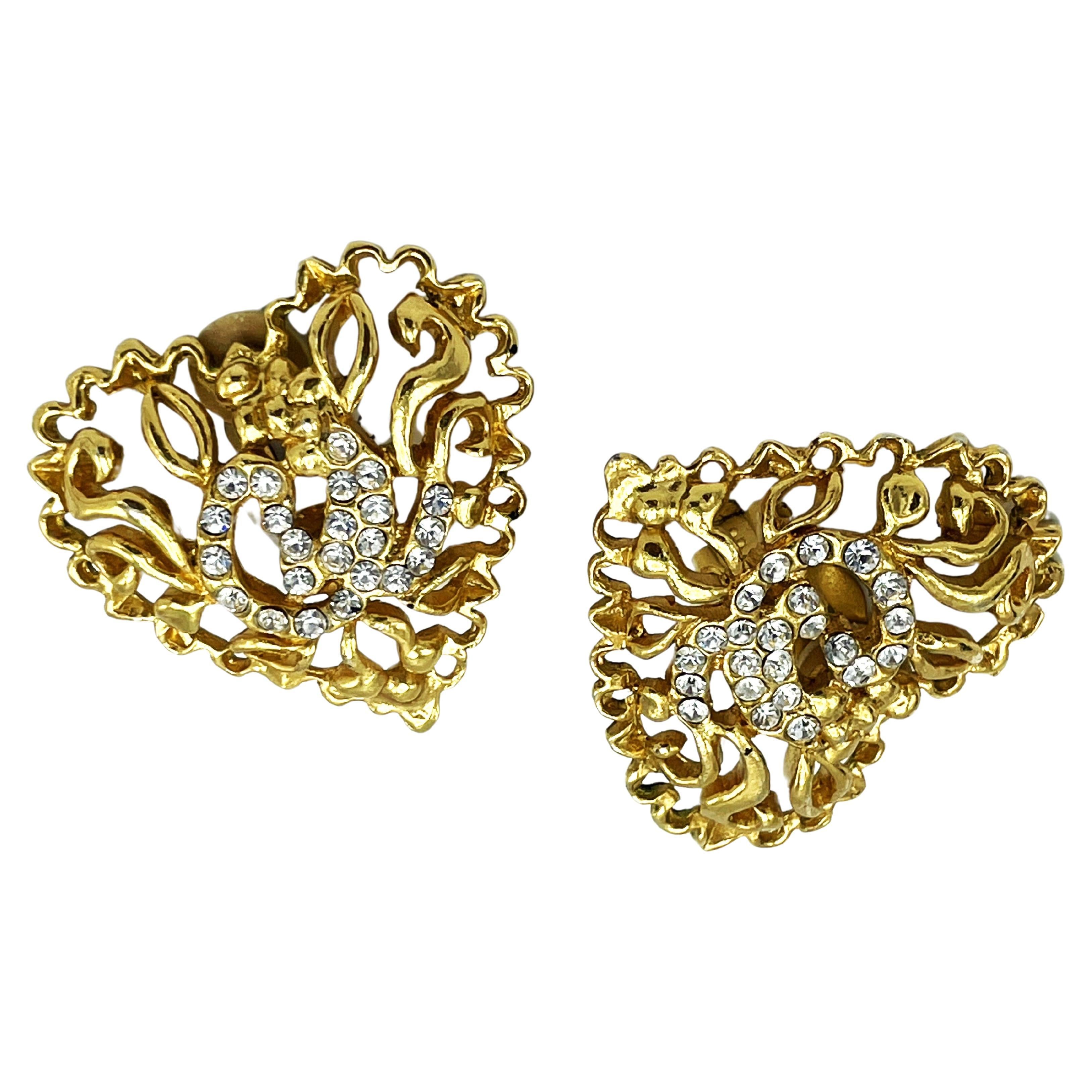 Clip-on earrings in the shape of an openwork heart, with Lacroix signature in rhinestones in the middle.

Dimensions: 
Width  4 cm  x H 4 cm 
Futures:
- Original Christian Lacroix stamp and date summer E94
- Openwork with Lacroix signature in