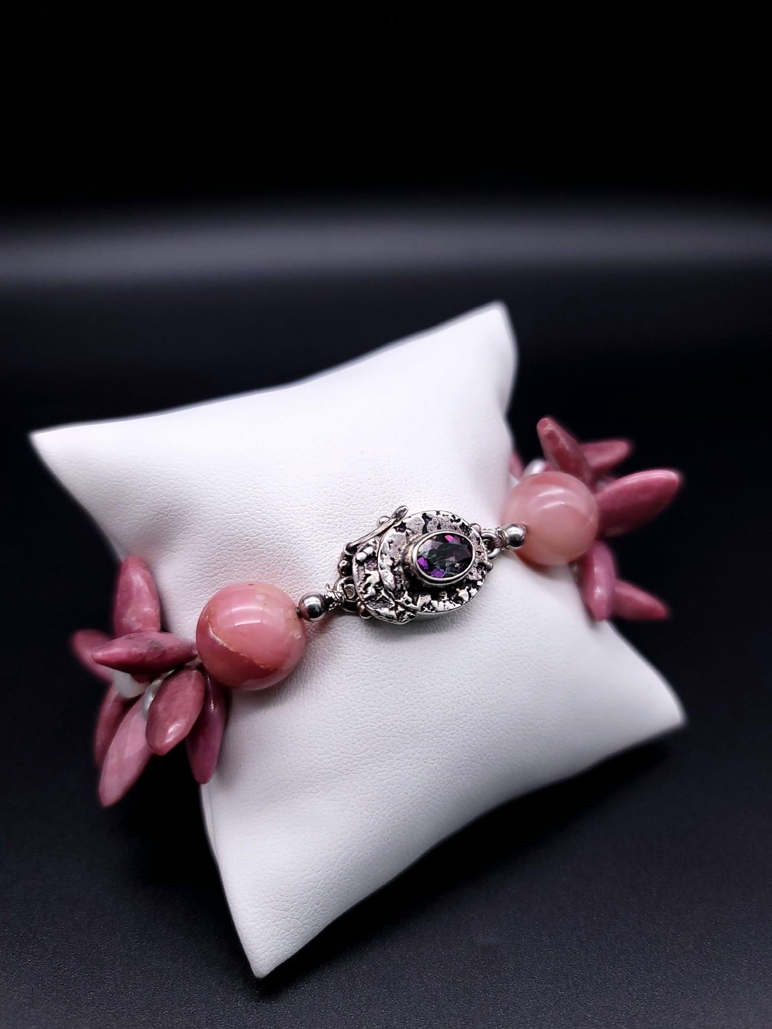 One-of-a-Kind

If you are a bracelet collector this is a must-have. Pink faceted Rhodochrosite petals accented with 5mm pearls join to make a wrist ruffle caught up with an elegant sterling silver and tourmaline clasp.
Silk hand-knotted
Approx: 8