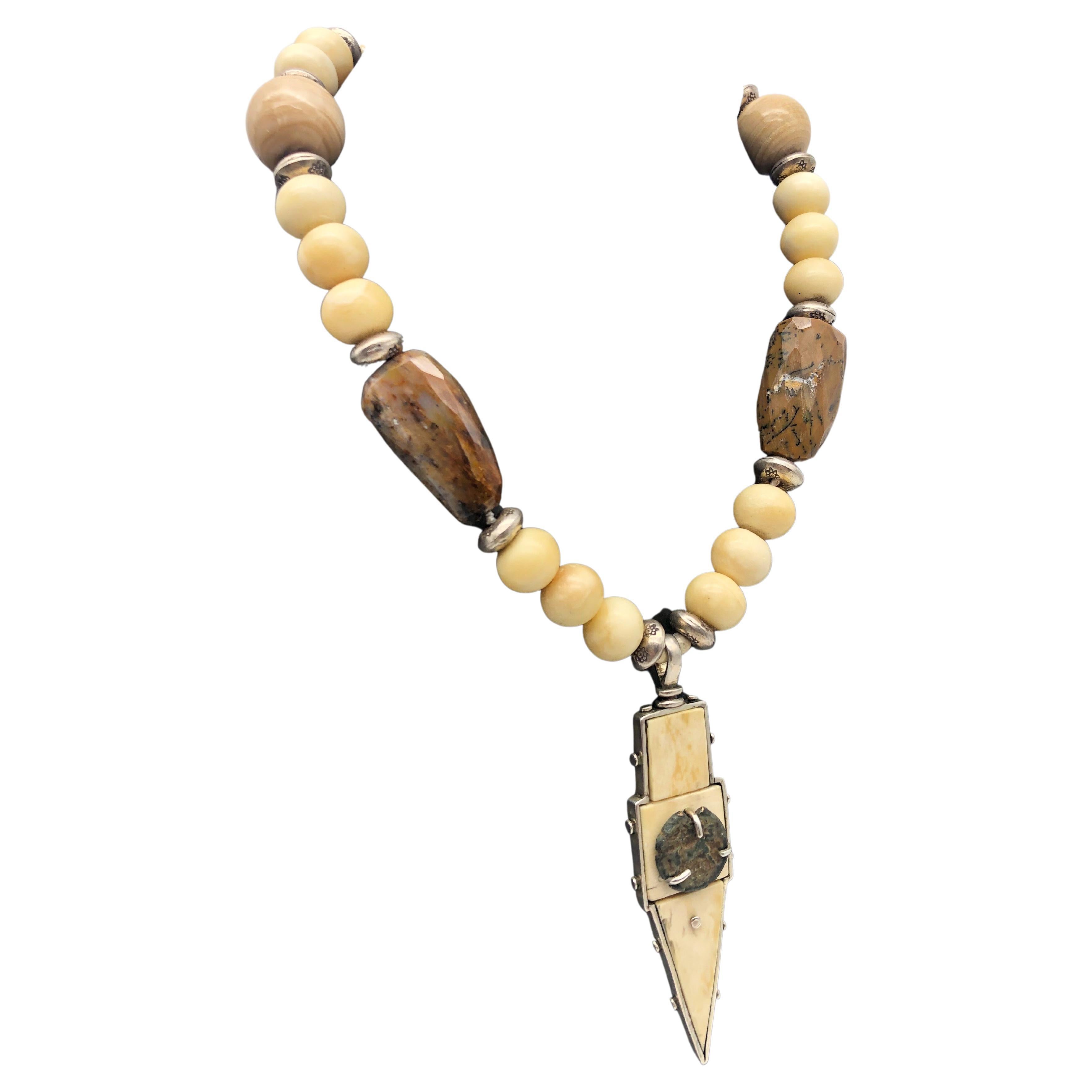 Unique en son genre

Le pendentif est un mélange d'argent sterling, d'os de morse préhistorique et d'une ancienne pièce de monnaie romaine. Il est accompagné d'un collier coordonné aux couleurs douces et monochromes de jaspe poli et de perles