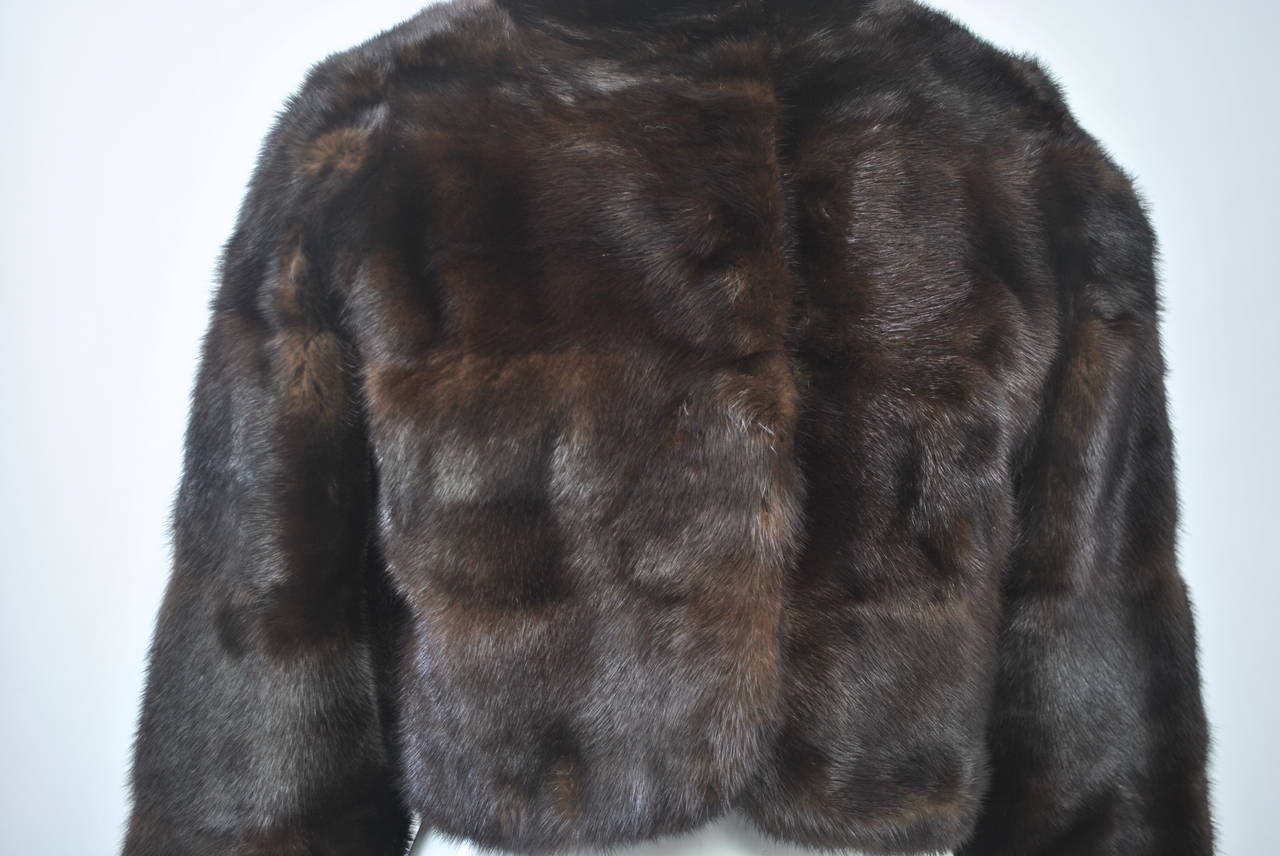 This rich and supple mahogany mink bolero jacket by Revillon features vertical skins, a stand-up collar, and bracelet-length sleeves. Closes with 2 fur hooks. Lined in black satin. Great styling and quality. Small size - approximate 2-4.