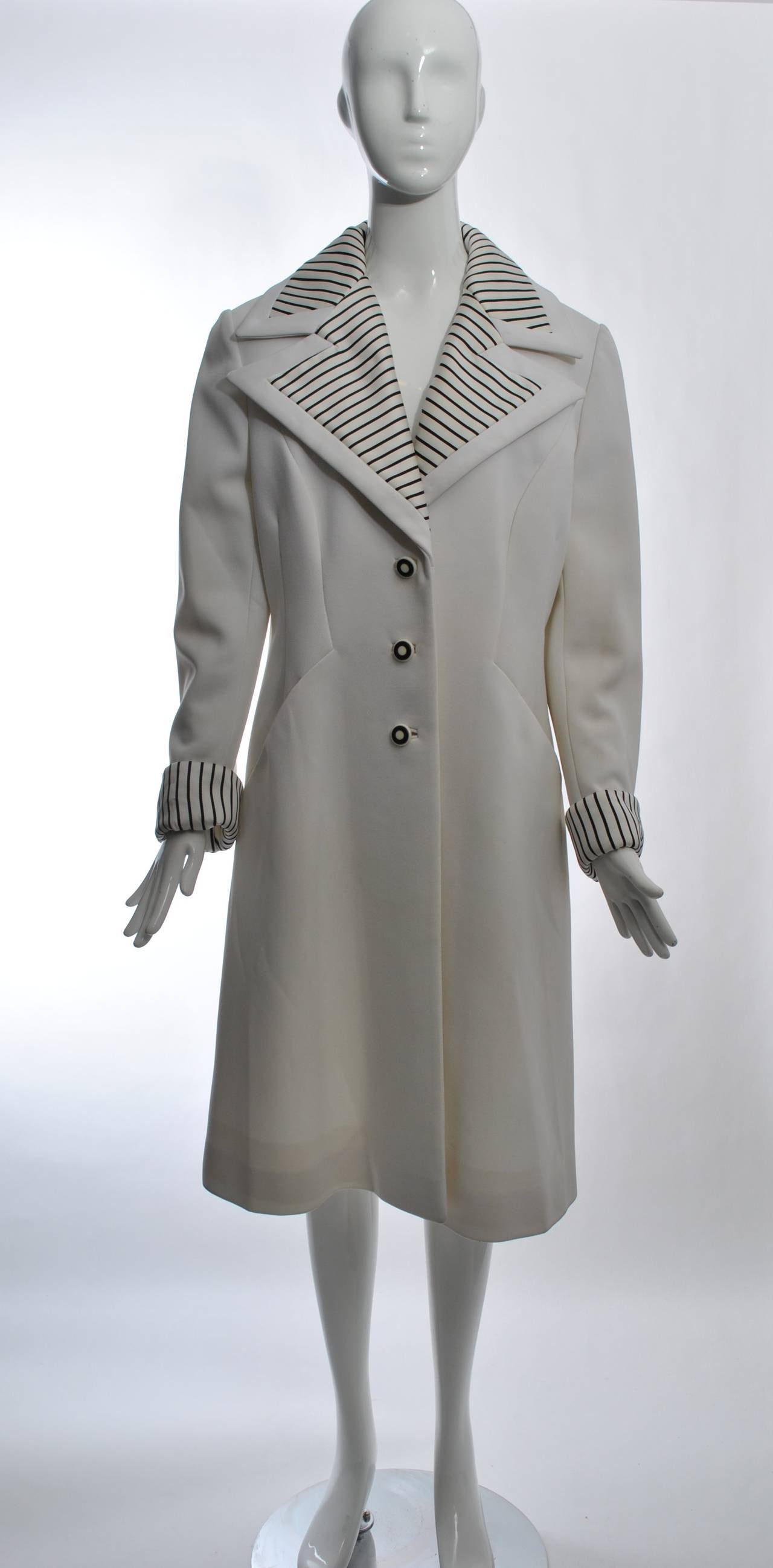 Lilli Ann white polyester coat with wide spread collar and cuffs faced in black and white stripes. Slanted, integral pockets, back belt, and black and white buttons complete the look. Size L.