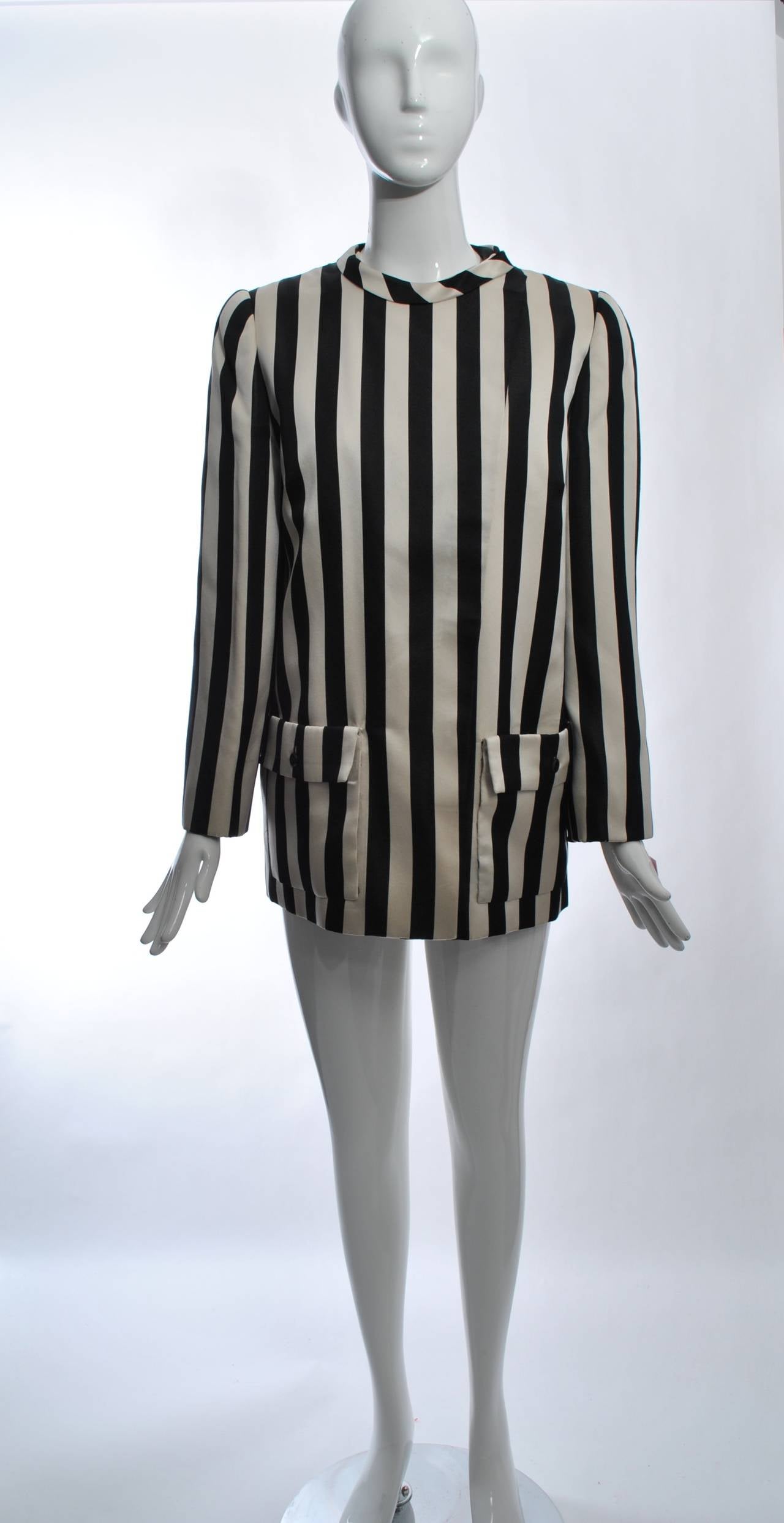 Andre Laug 1980s satin jacket in black and white vertical stripes featuring a  rounded neckline and patch pockets with hidden buttons under a placket down the front. Underneath is a collared vest in black satin with a white collar, belted in back.