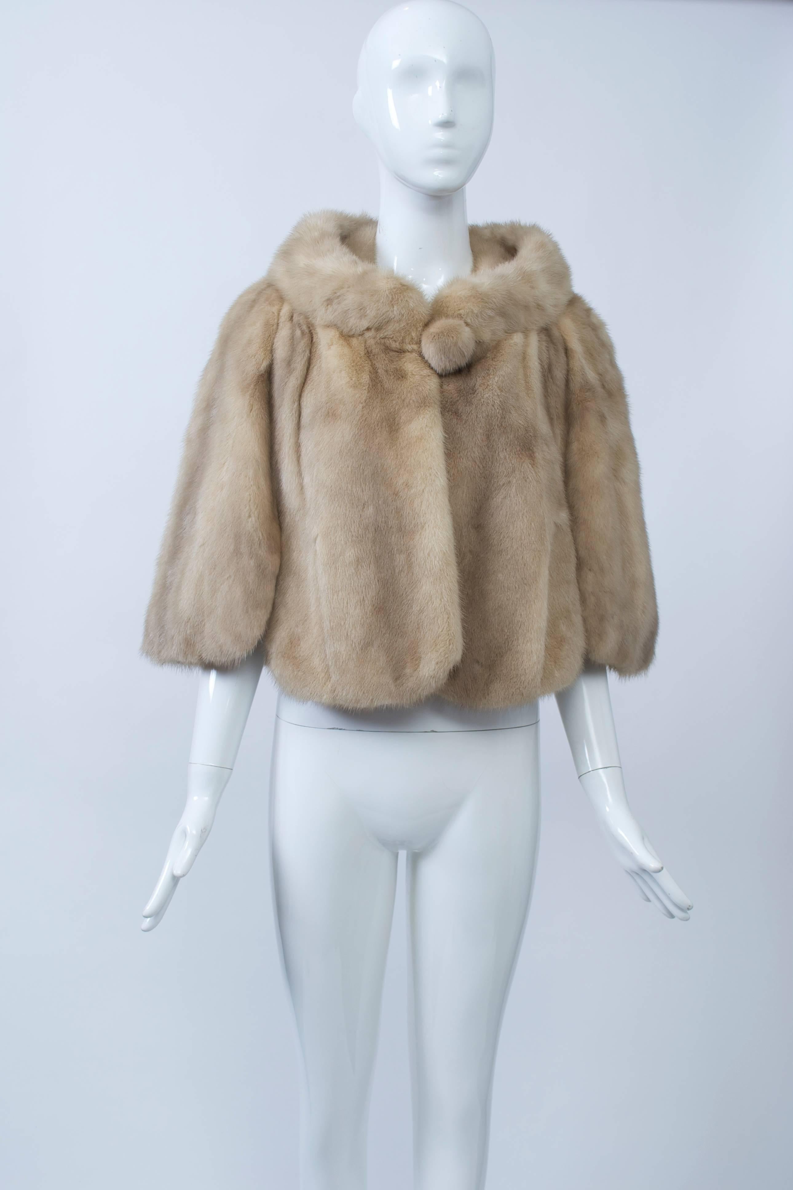 Honey mink 1960s capelet with stand-up collar, scalloped hem, and mink button  closure. Slit pockets, beige satin lining. One size.
