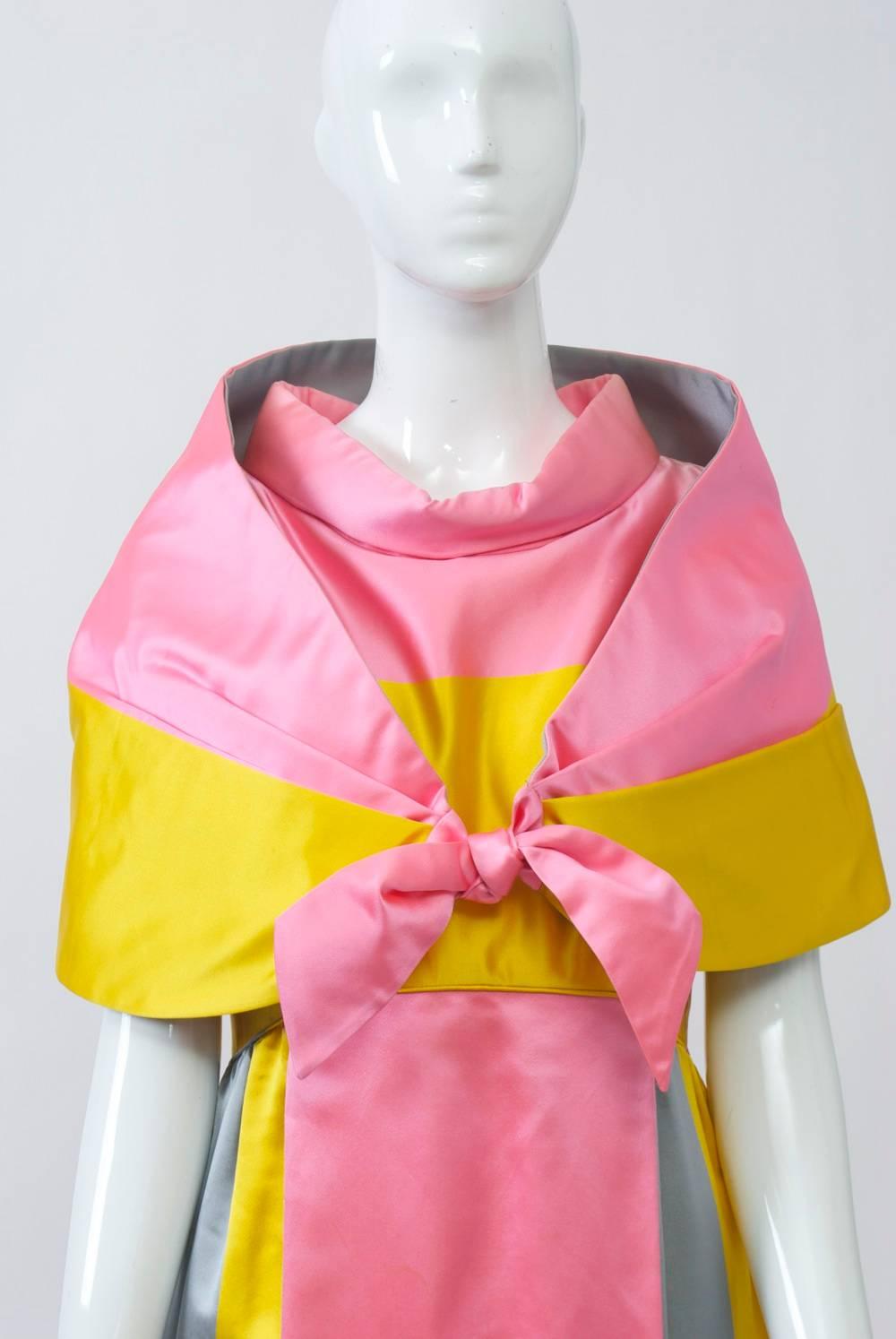Completely unique, this custom-made satin gown from the 1960s is a stunner. Fashioned of tricolor satin in bright pink, yellow and grayish blue, the designer used the fabric quite creatively, with a deep border at the hem on the diagonal. The