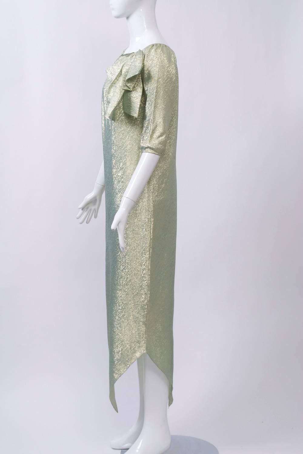 Easy wearing, long shift with handkerchief hem, 3/4 sleeves, and shirred scoop neck finished with a large bow. Fabricated of a lightweight synthetic in aqua and gold. No label, but attributed to Halston.
