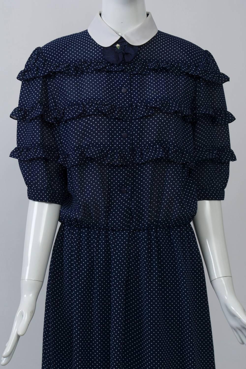 Hanae Mori modified shirtdress in a sheer and lightweight navy fabric with white micro dots features narrow rows of ruffles on the bodice and elbow-length sleeves, as well as a white peter pan collar. An elasticized waist creates a blouson style on