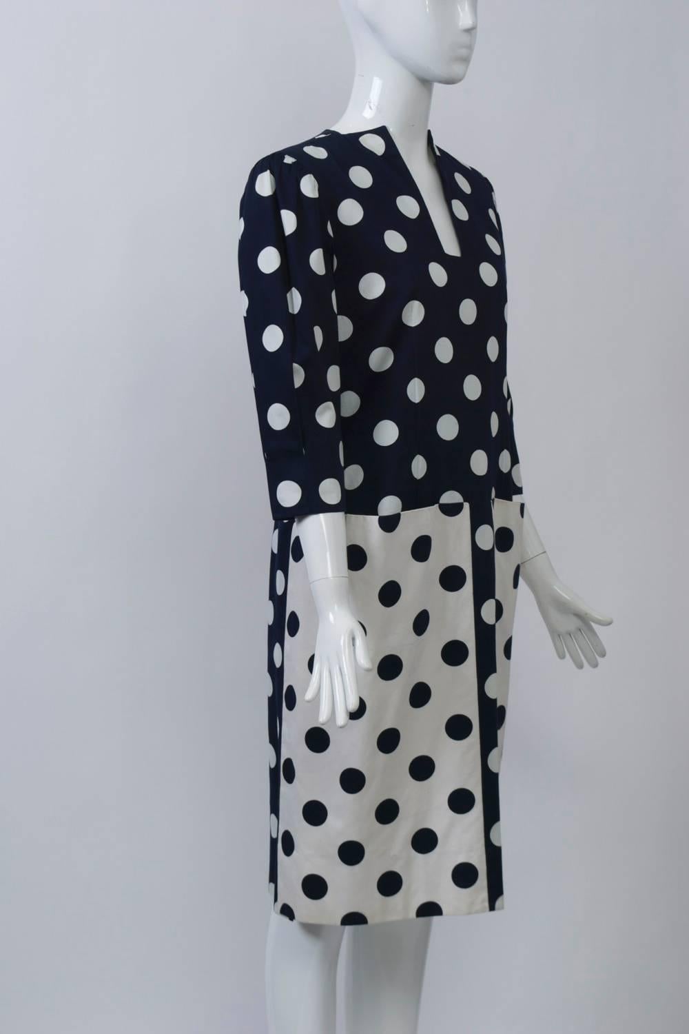 Robe des années 1980 Pauline Trigére en coton poli, imprimée de pois inversés marine/blanc et présentant le souci du détail propre à la créatrice. Le corps de la robe, de couleur marine à pois blancs, présente une encolure fendue inhabituelle et des