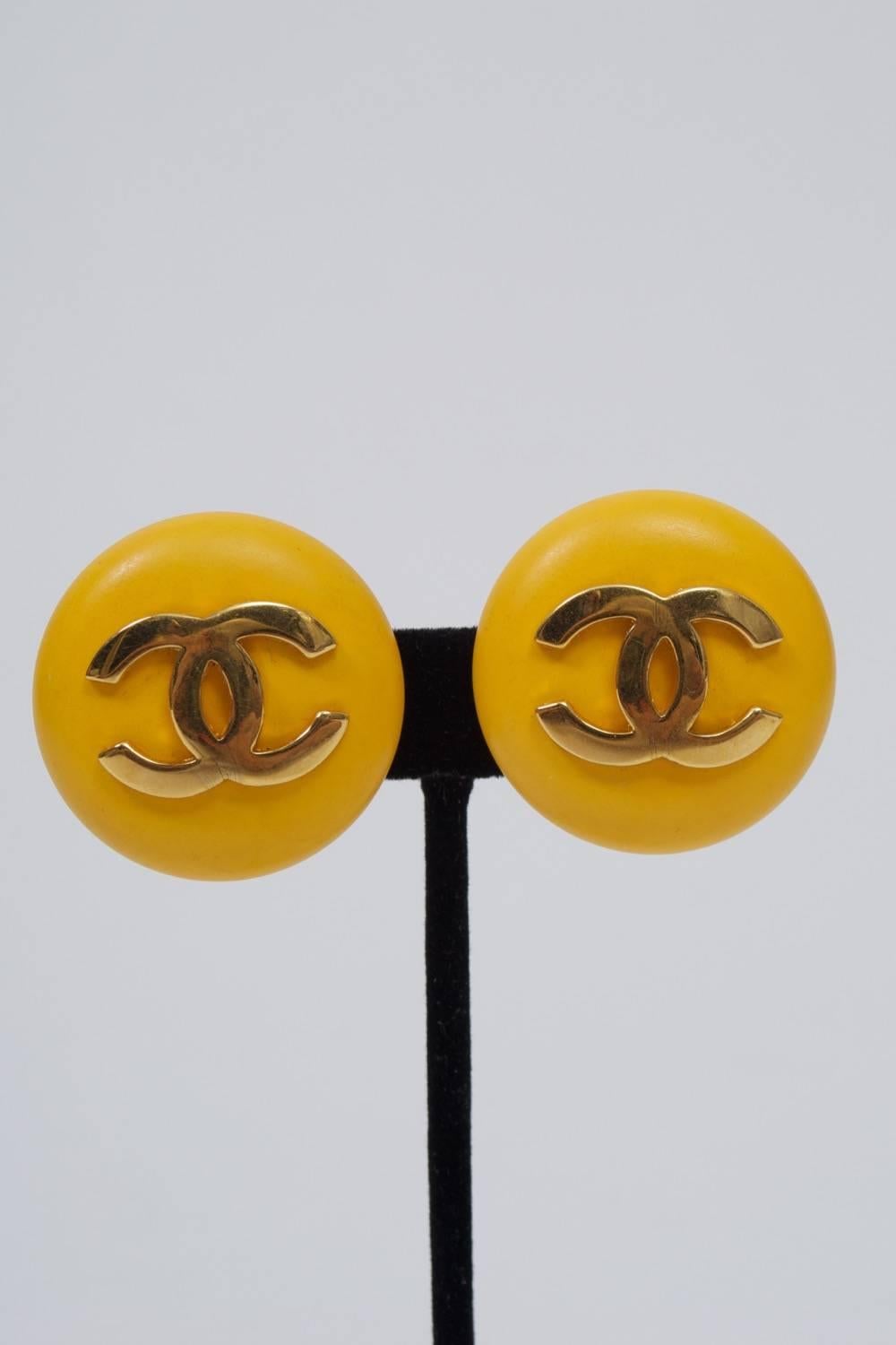 Classic Chanel button earrings in yellow plastic or resin with double-C logo in gold metal. Clip backs with oval identity plaque dating design to 1987.