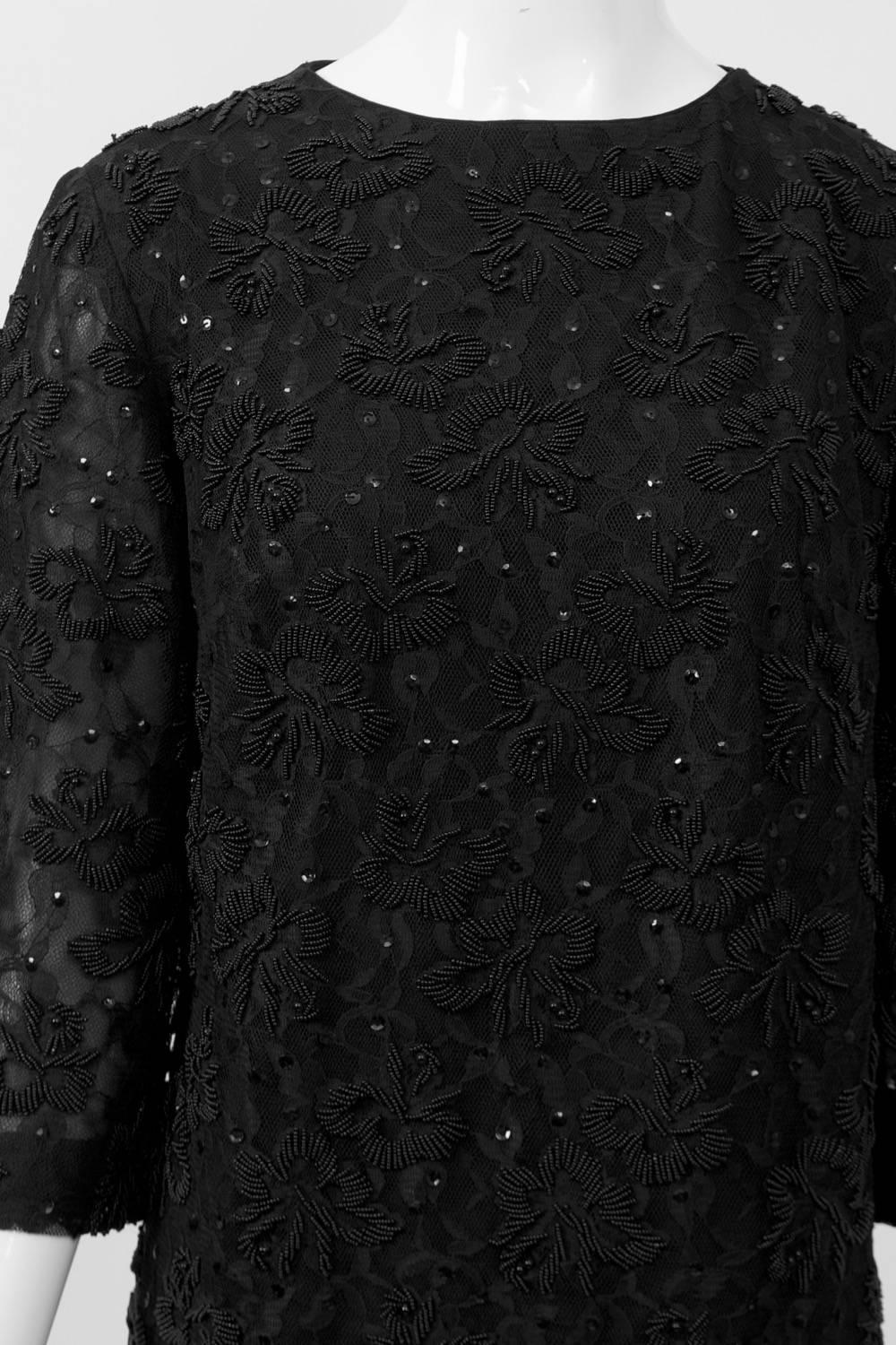 Classic and timeless cocktail dress in black lace with black floral beading throughout. Simple sheath styling with round neckline, three-quarter sleeves and  metal zipper in back. Dress lined, sleeves semi-sheer for a nice touch. Marked size 12, but