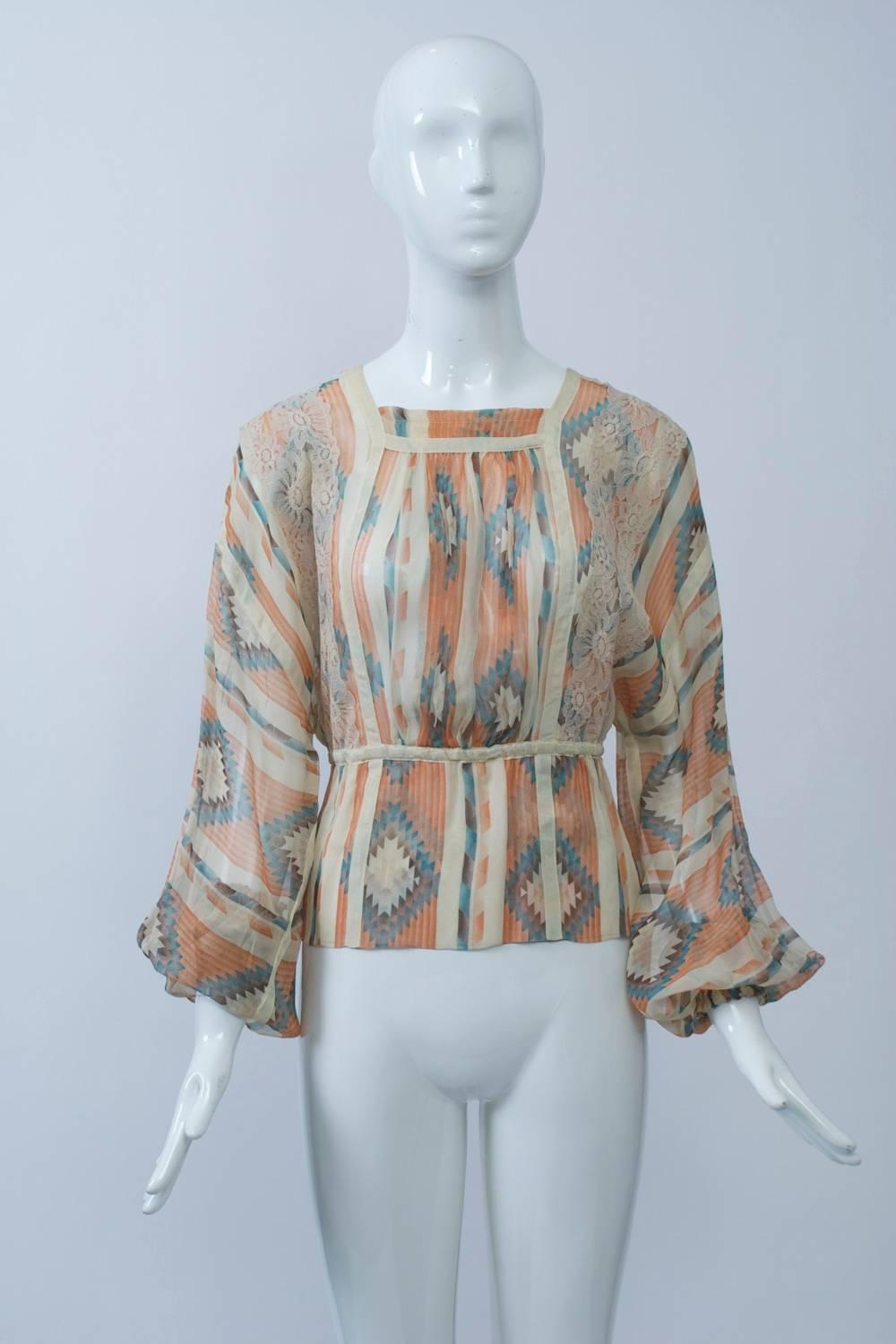 Koos van den Akker 1970s blouse in a sheer, native American-inspired print in shades of ivory, coral and turquoise. The blouse features a shallow square neckline, billowy sleeves with elastic wrists, an elastic waist, ivory and lace trim, buttons