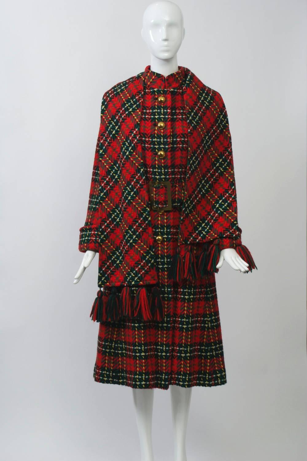 Wonderful red plaid coat featuring a wide belt, mandarin collar, and turn-back cuffs, accented with a fringed scarf. Fitted bodice, slight A-line skirt. Lined in green crepe. Excellent condition. Size S.