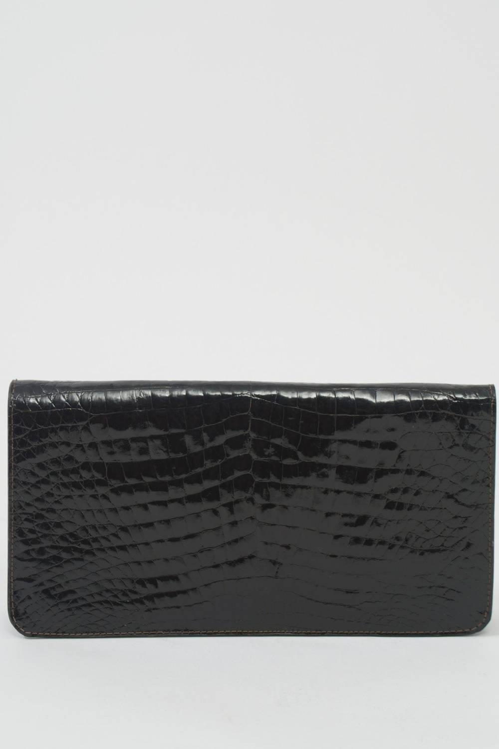 Simple, classic, and timeless, this black crocodile clutch from Charles Jourdan has a foldover flap that closes with a snap. Interior is lined in black leather and has a side compartment. Skins in excellent condition.