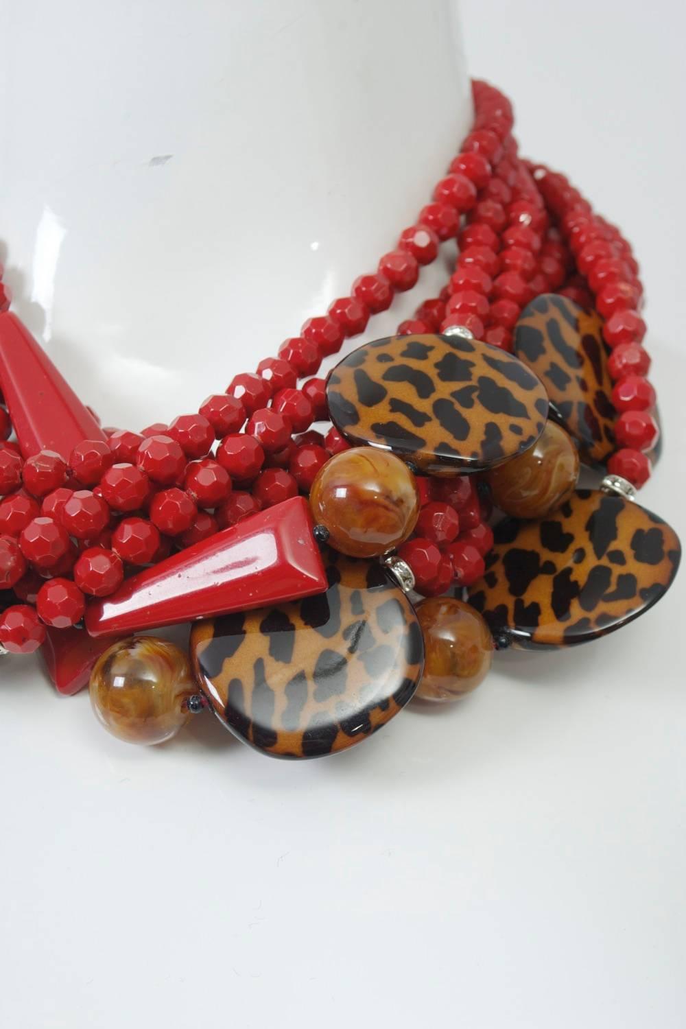 Eye-catching multi-strand necklace by Italian designer Angela Caputi, composed primarily of coral-red beads accented asymmetrically by matching elongated beads and contrasting large spotted disks. Magnetic black clasp.