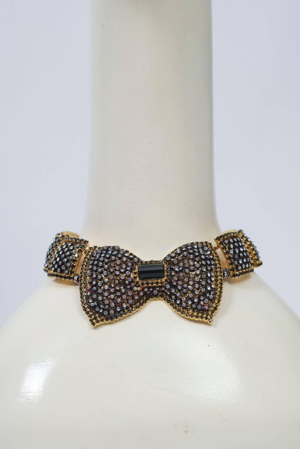 A prime example of the sought-after costume jewelry by William DeLillo, known for his runway pieces, this collar is composed of heavy gold metal links centering a large bow, each component embellished with rhinestones set in black mesh and