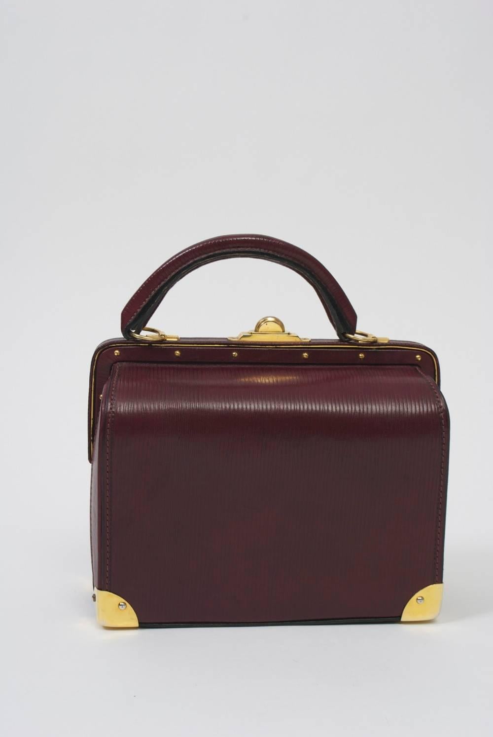 Impressive doctor's style satchel by Roberta di Camerino in a rich dark plum leather that has a striated texture. The structured handbag features unique hardware in polished gold metal, which include the slide-up and pull closures on the exterior