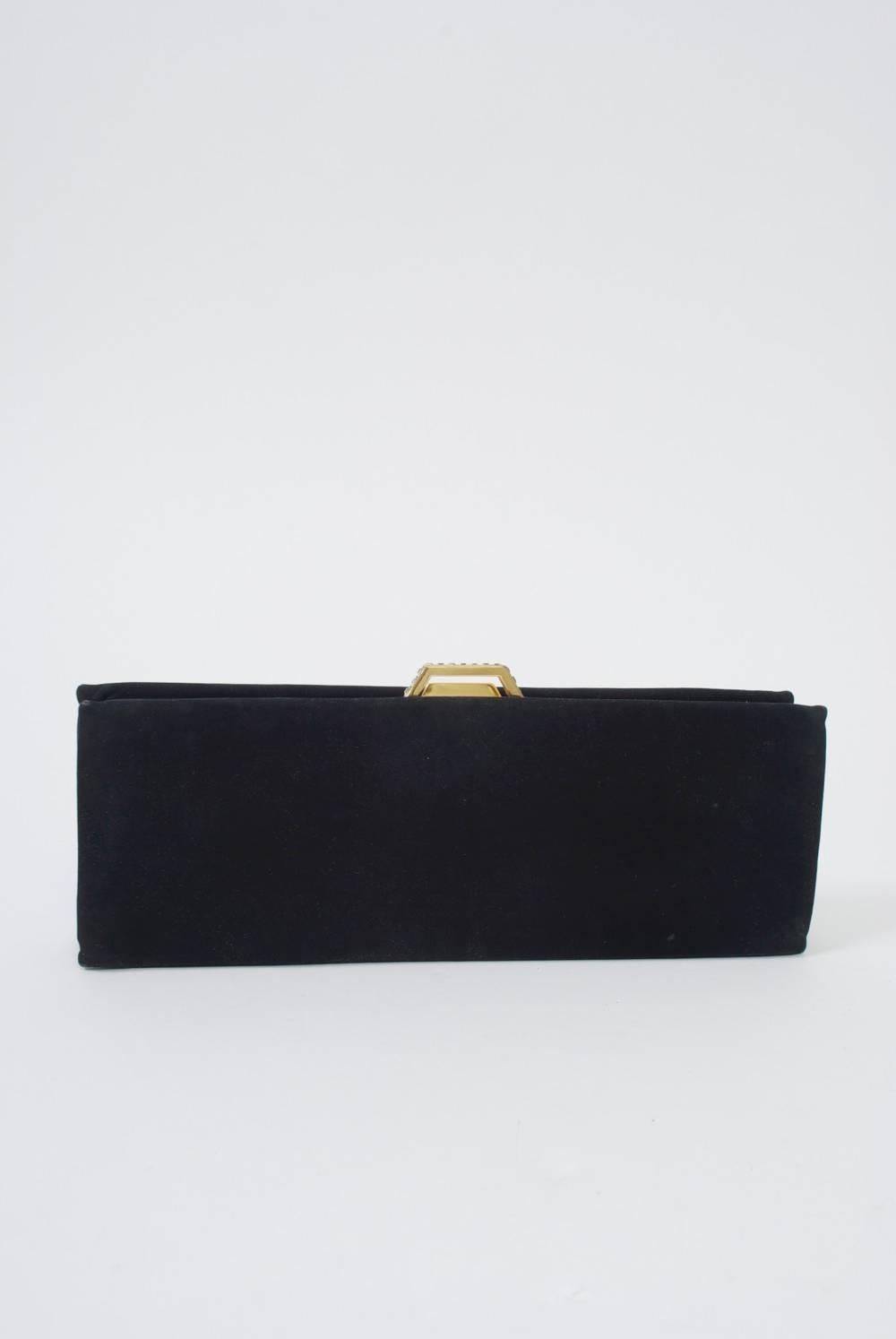 Sleek and elongated black clutch in black suede with rhinestone-studded goldtone clasp. Black taffeta interior with slip compartments, comb, mirror and change purse. A classic from one of America's foremost vintage handbag companies.