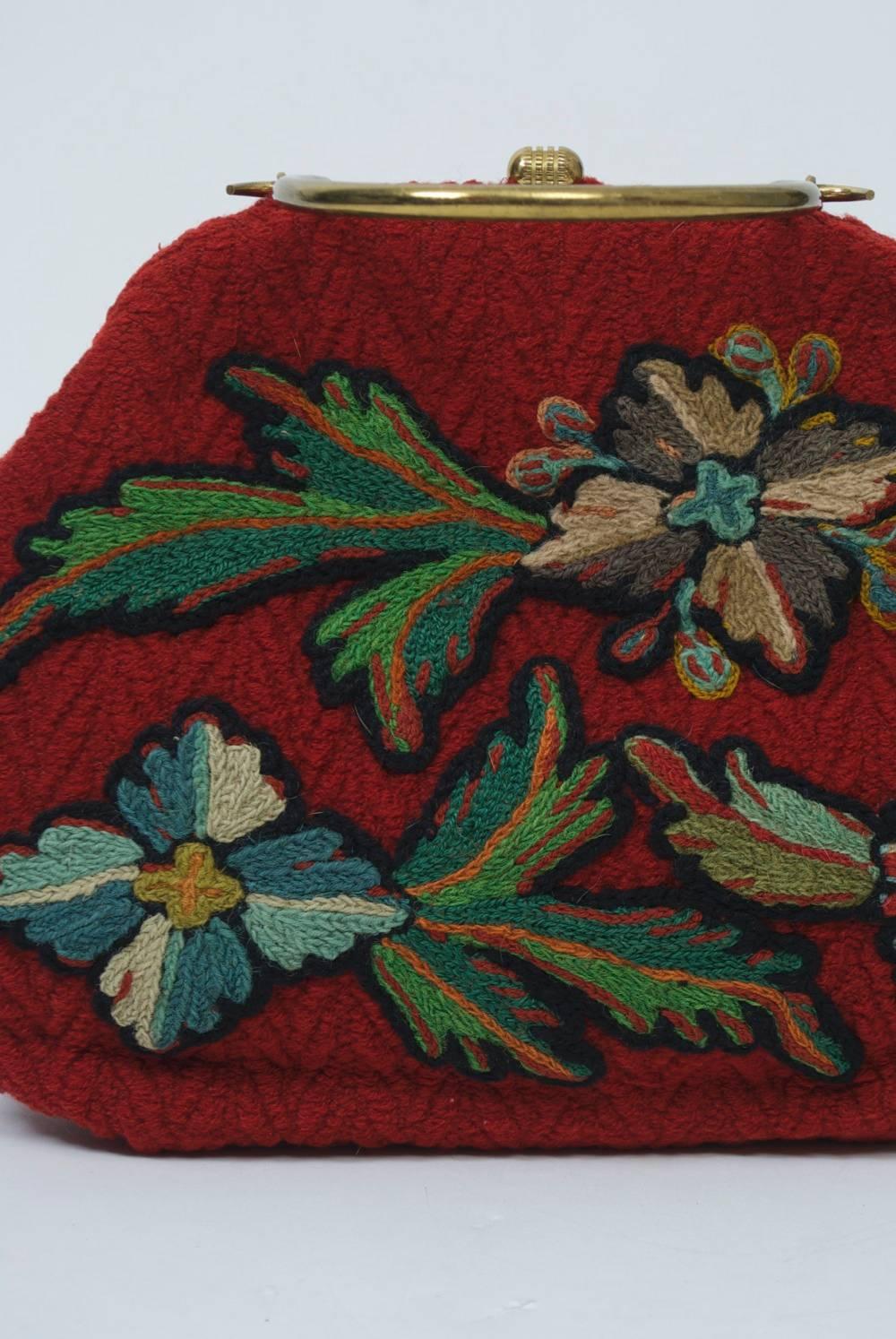 Morris Moskowitz was one of America's premiere handbag manufacturers, producing articles with great style and craftsmanship. This is an unusual example of their work, in red wool ground with multi-colored crewelwork appliqué. Rolled metal handle