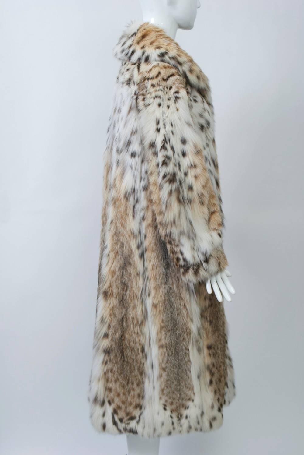 Full-length coat, c.1970s, of spotted lynx fur. Single breasted with large collar that can stand up or be fastened tight for extra warmth. Side slit pockets. Approximate size Small.