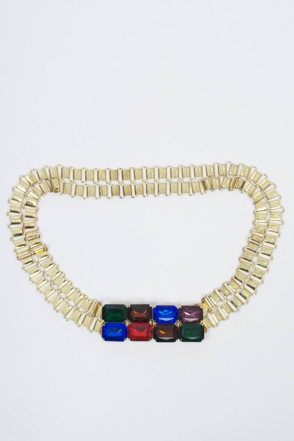 Double row gold metal link belt featuring a large clasp consisting of six rectangular, multicolored crystals. 
