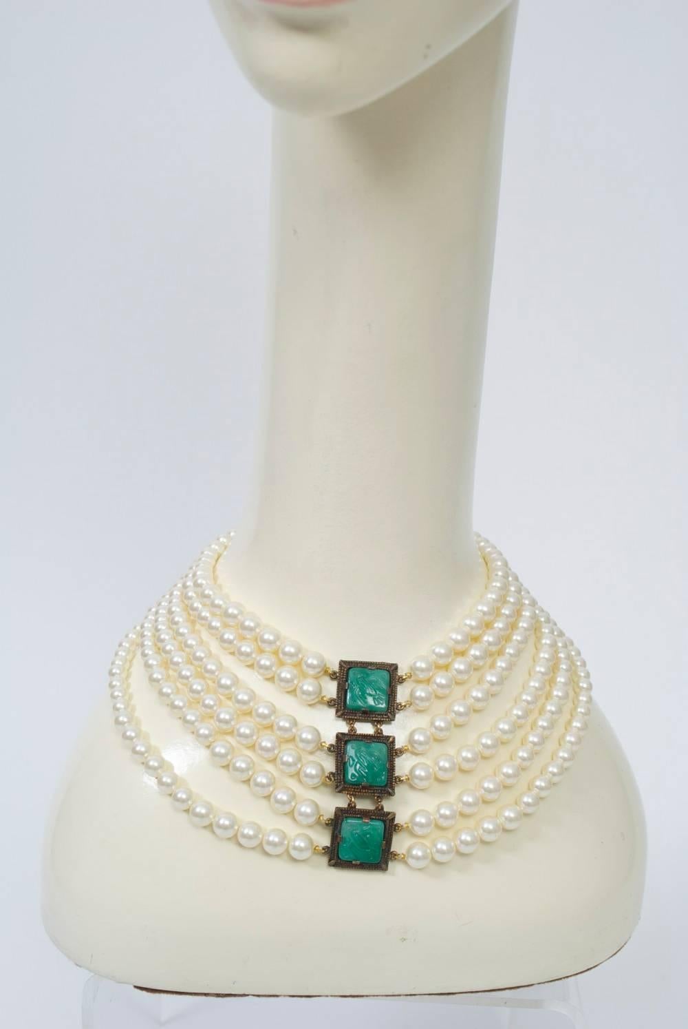 Marvella multistrand pearl bib necklace centering a central set of three faux jade medallions in dark metal frames. Adjustable hook closure in back.