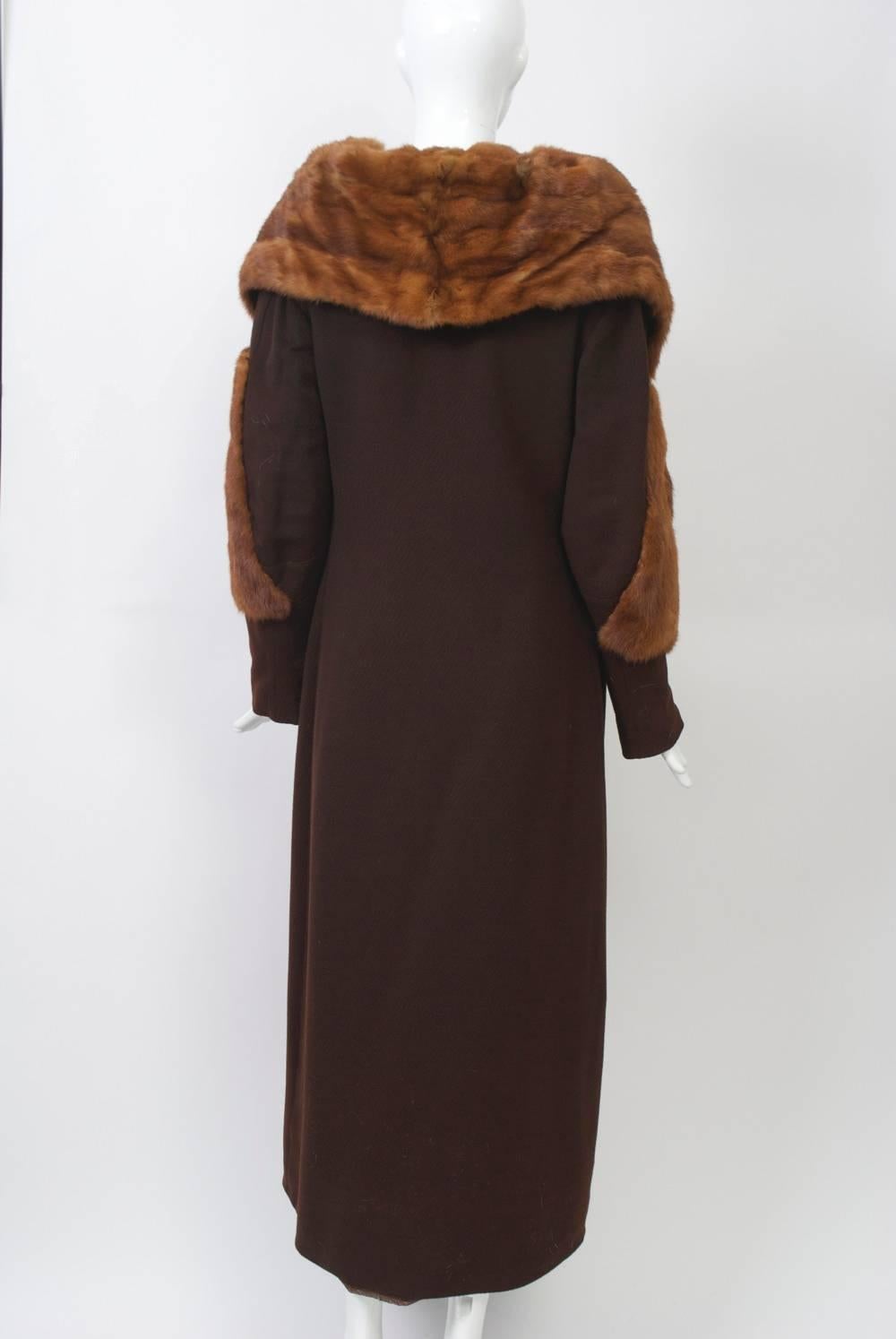 Brown wool 1930s long coat with golden mink trim on oversized stand-up collar and on sleeves. Asymmetrical closure with brown plastic buttons and interior closure. Narrow, slim cut, brown satin lining.