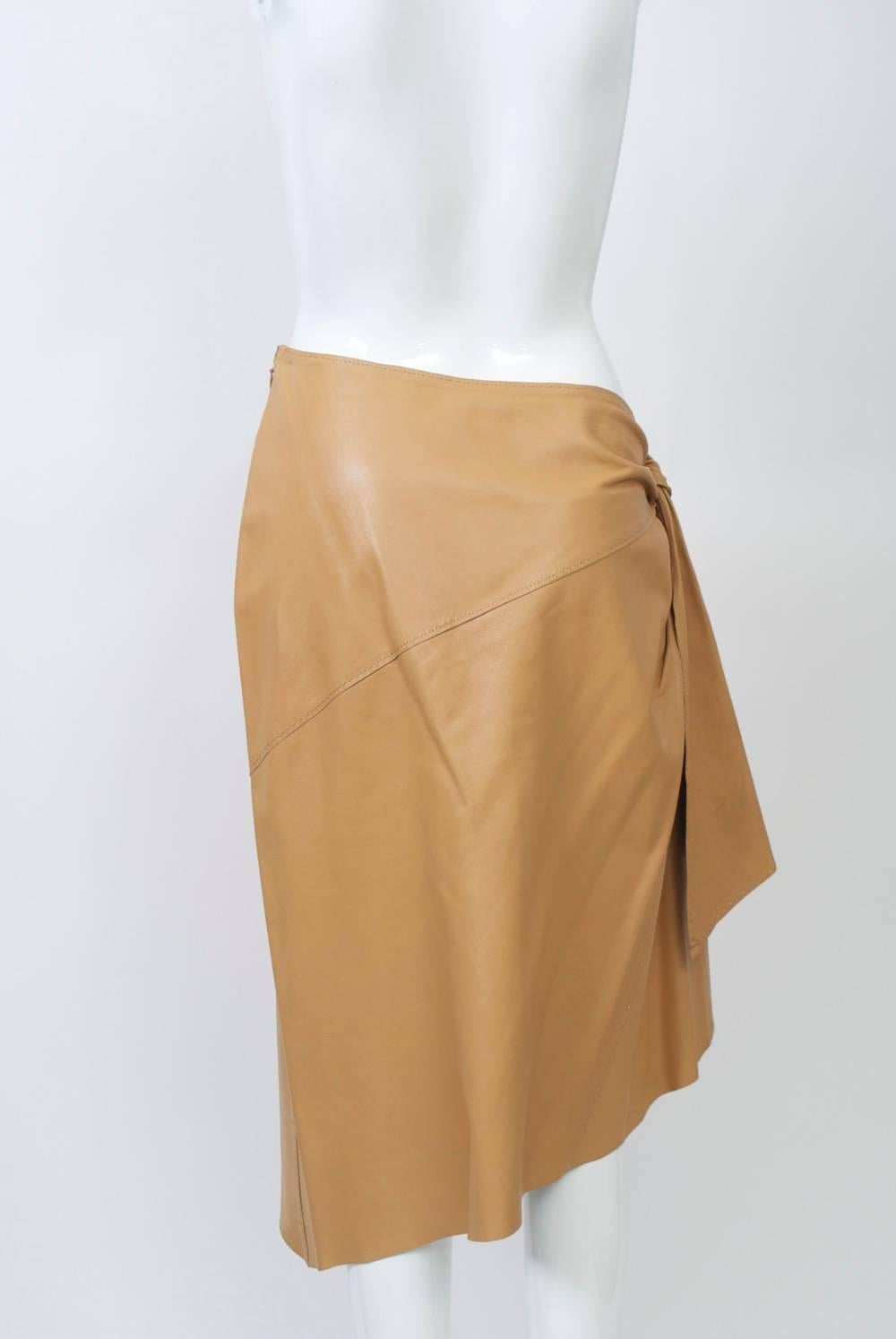 Sarong-style skirt by Hermes in softest camel lambskin with asymmetrical waist and hem. Zipper on the high, left side slants to tiered tie motif on the right hip with opposed diagonal seaming front and back.
